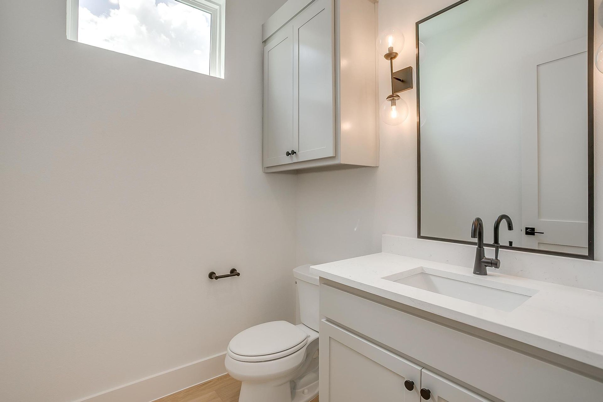 A bathroom with a toilet , sink and mirror.