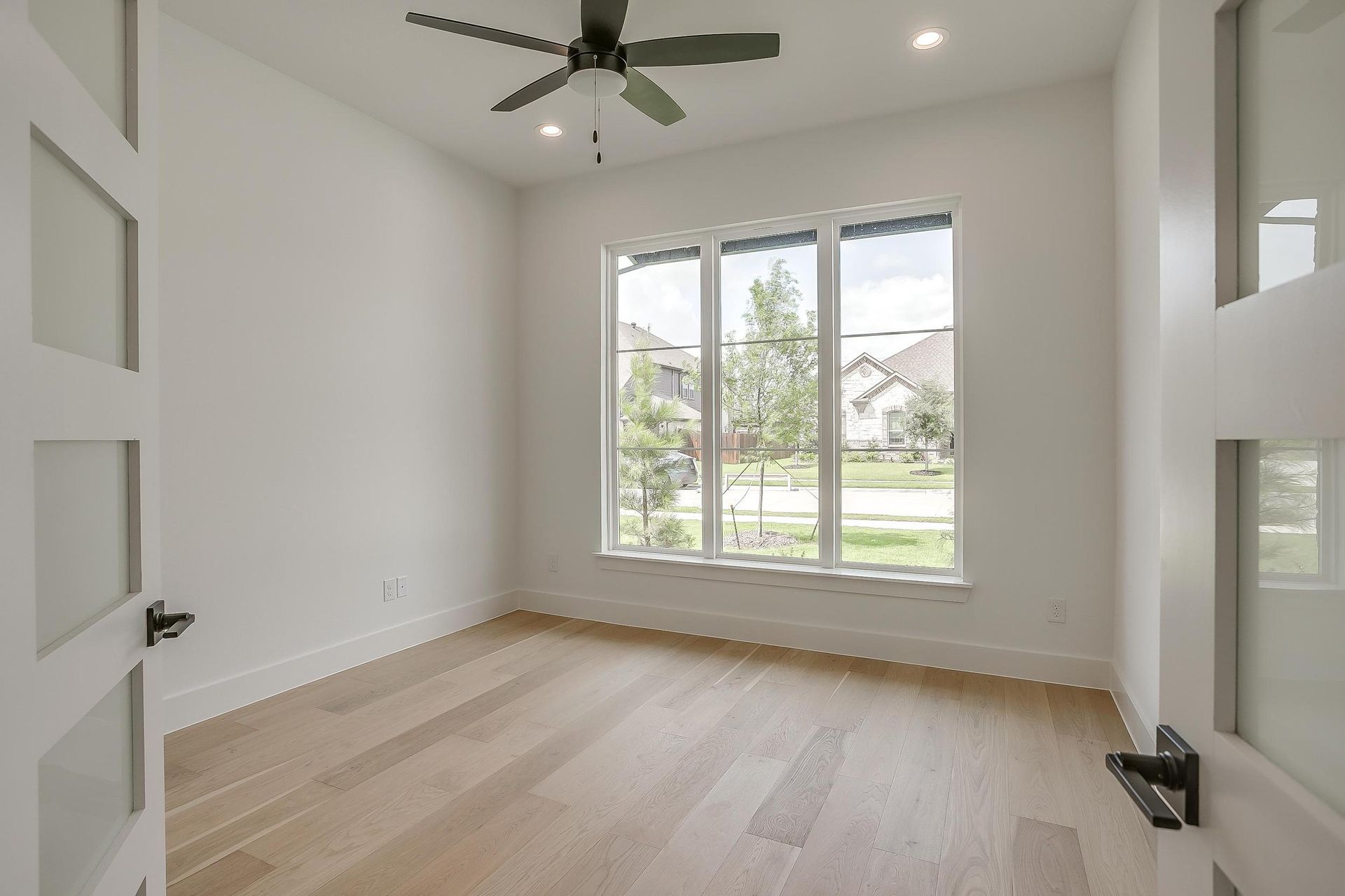 An empty bedroom with hardwood floors and a ceiling fan.