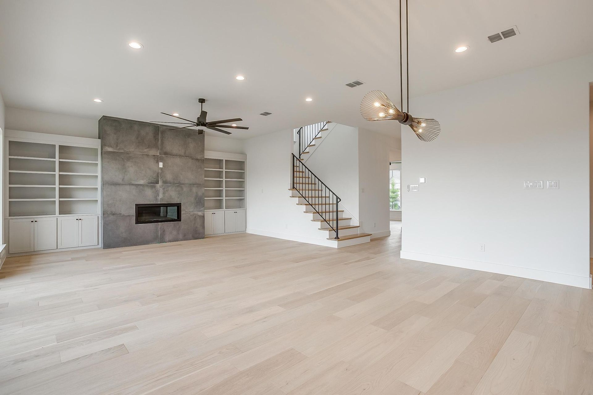 An empty living room with hardwood floors , a fireplace and stairs.