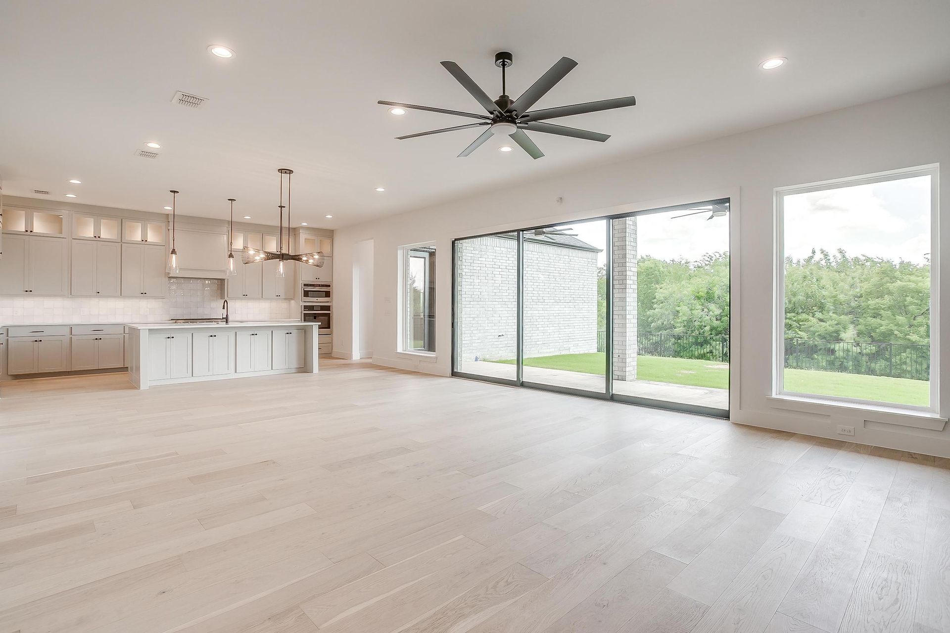 A large empty room with a ceiling fan and lots of windows.