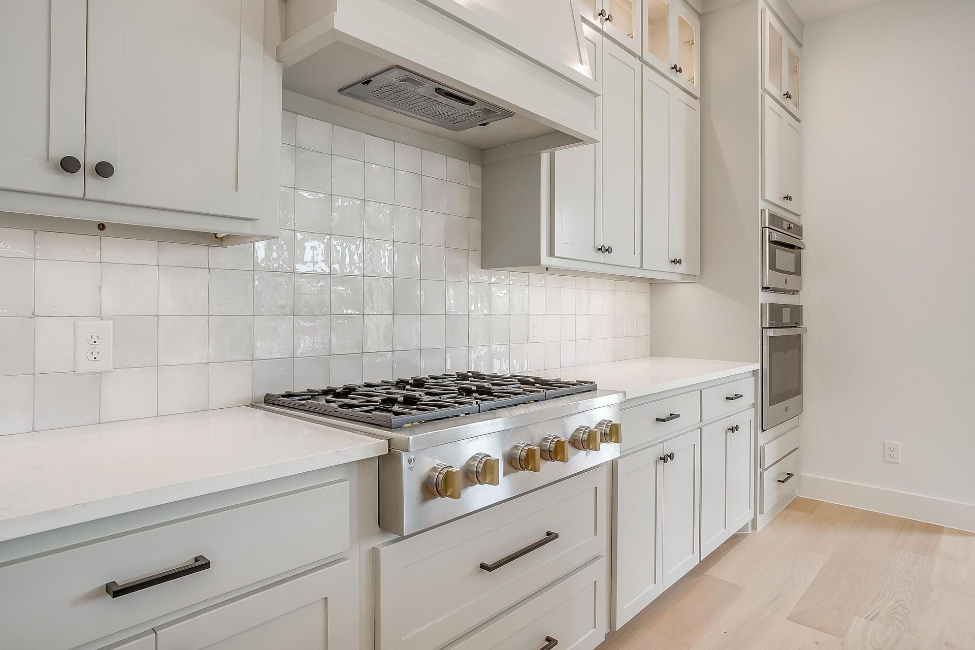 A kitchen with white cabinets and a stove top oven.