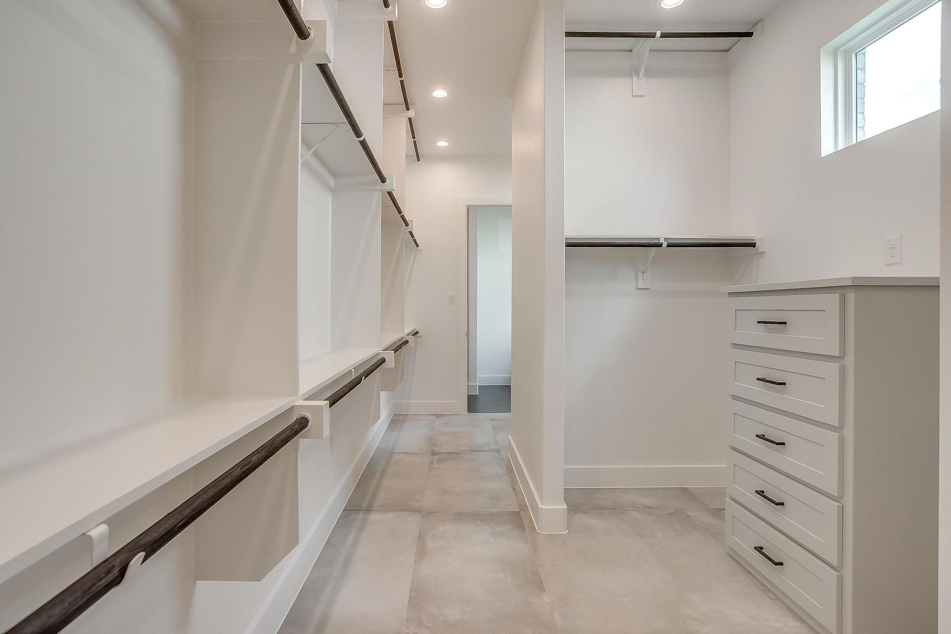 A walk in closet with lots of shelves and drawers in a house.