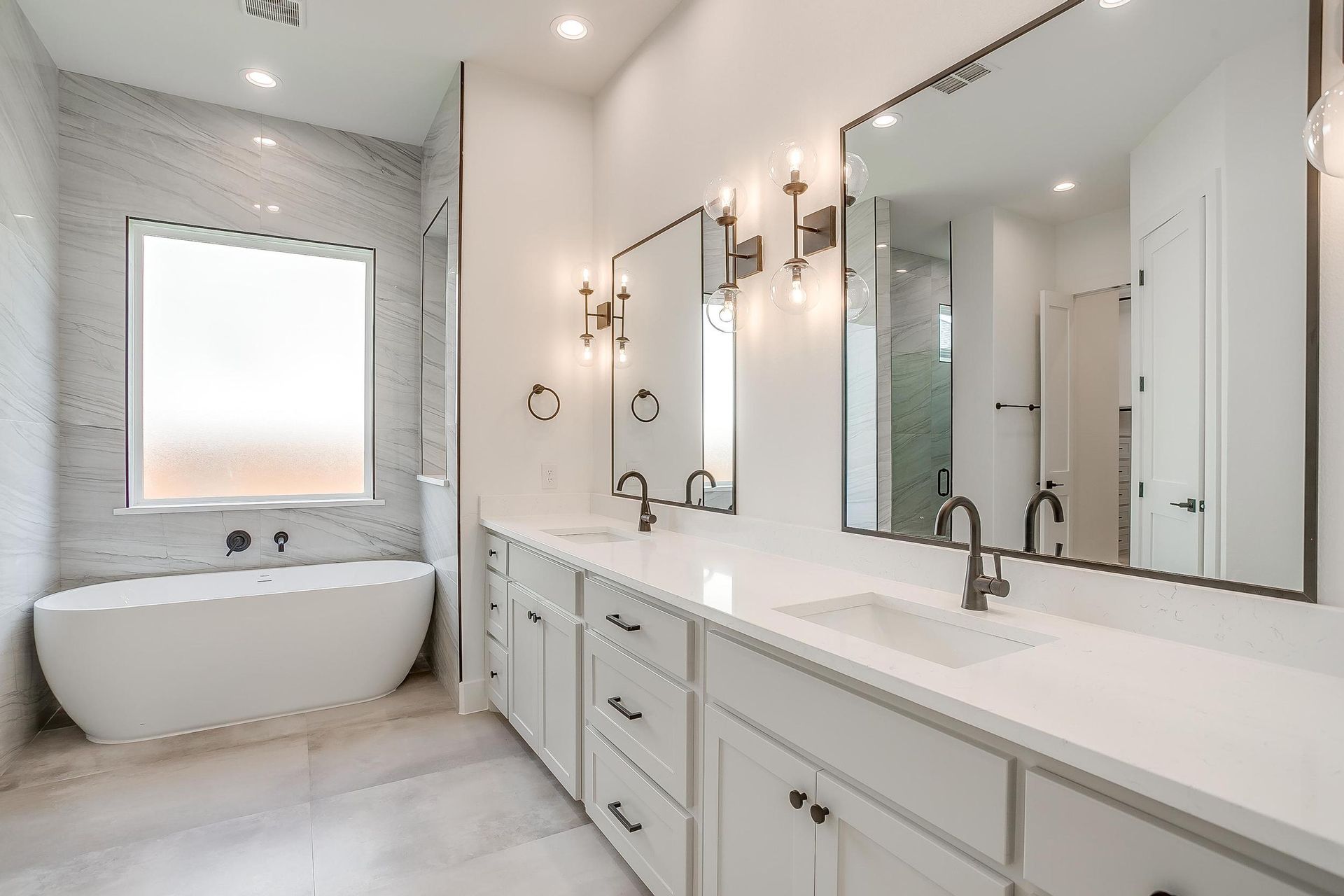 A bathroom with two sinks , a tub , and two mirrors.