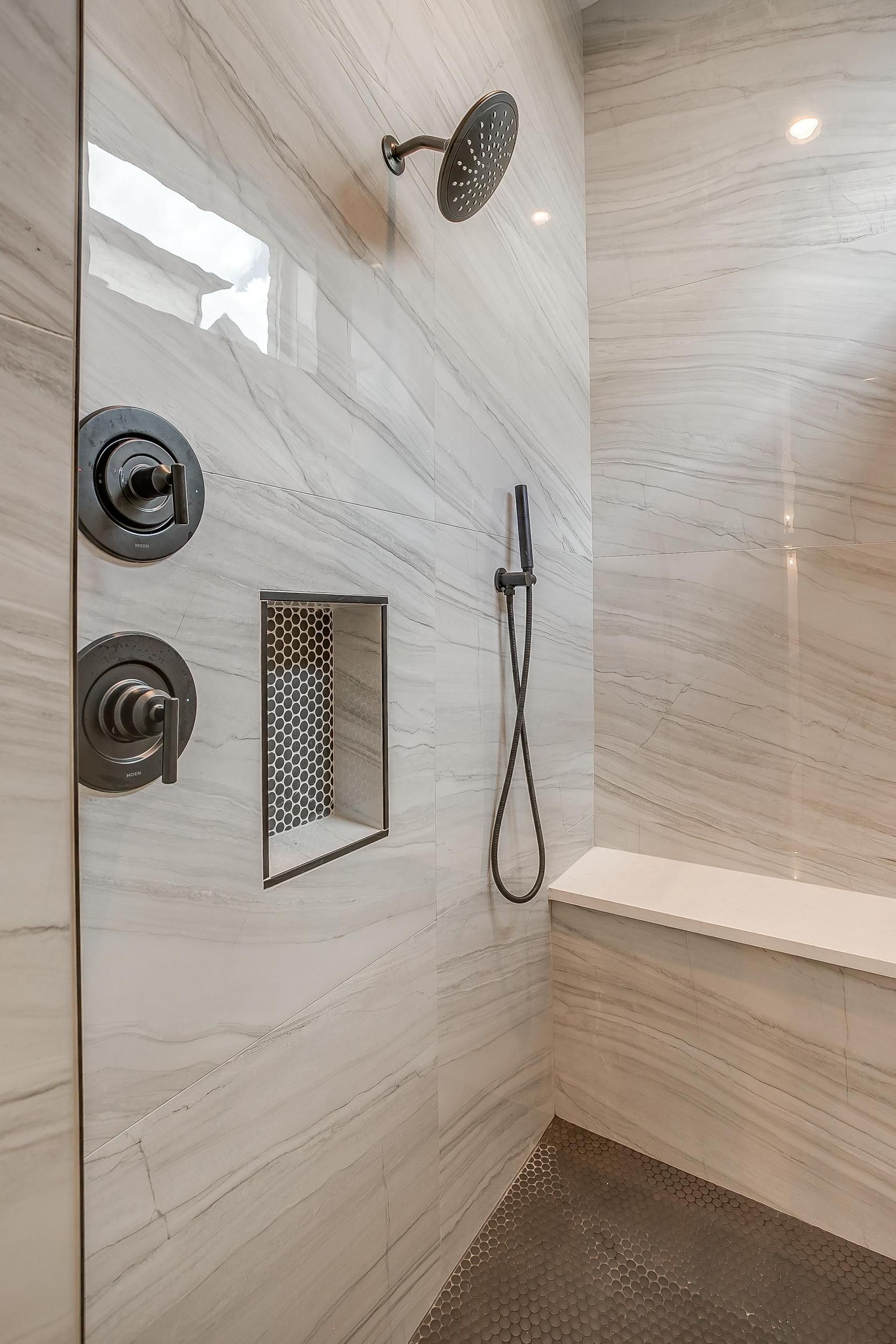 A bathroom with a walk in shower and a bench.