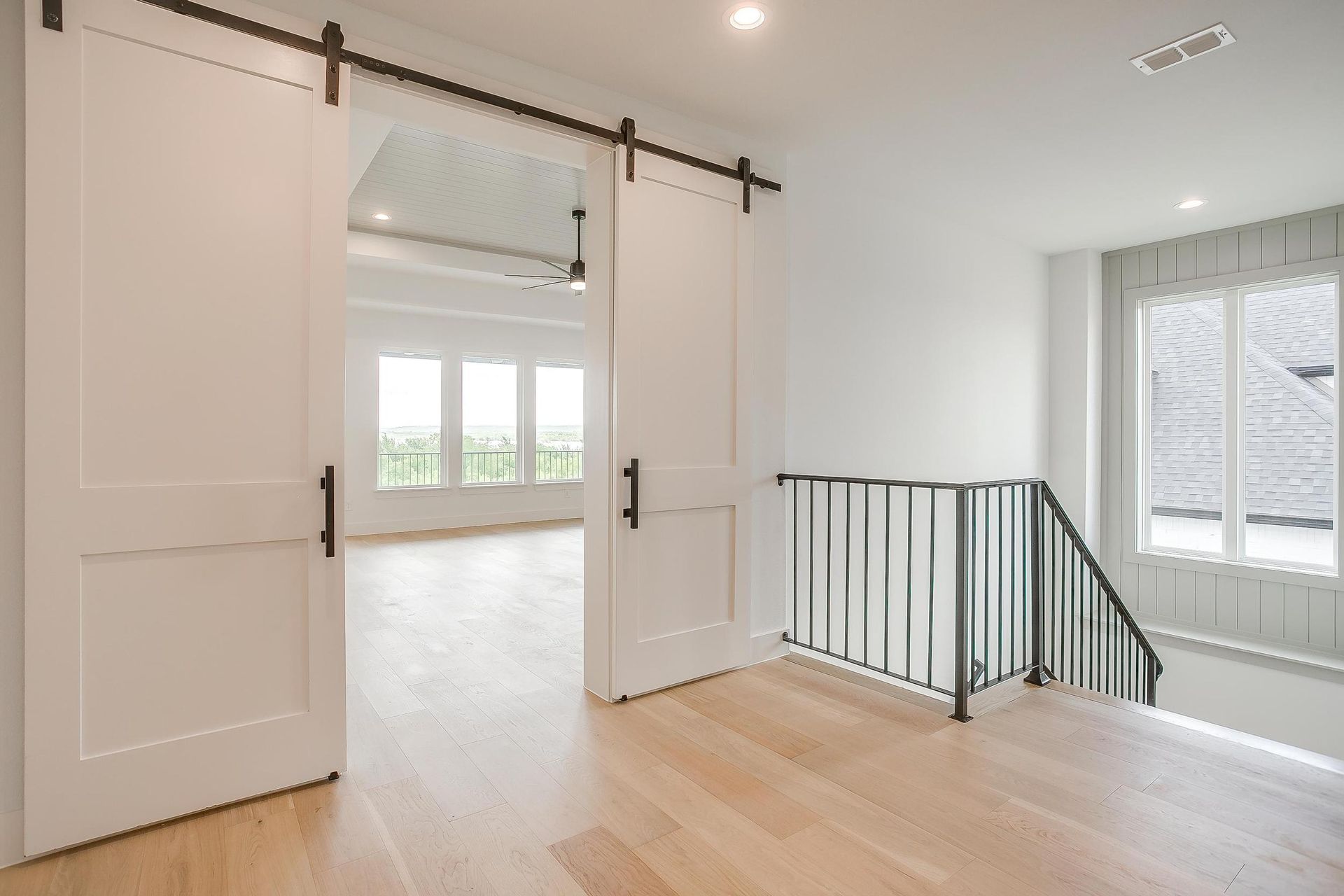 An empty room with sliding barn doors and a staircase.