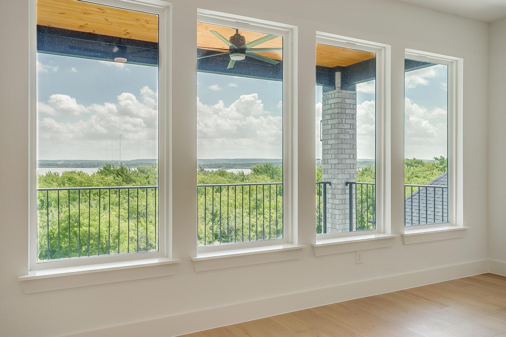 An empty room with three windows and a balcony overlooking a lake.