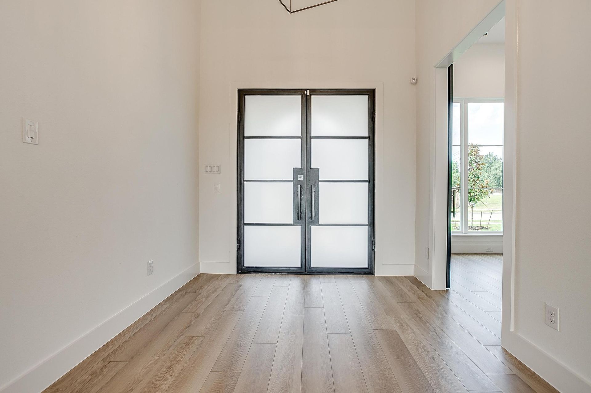 An empty room with hardwood floors and white walls.
