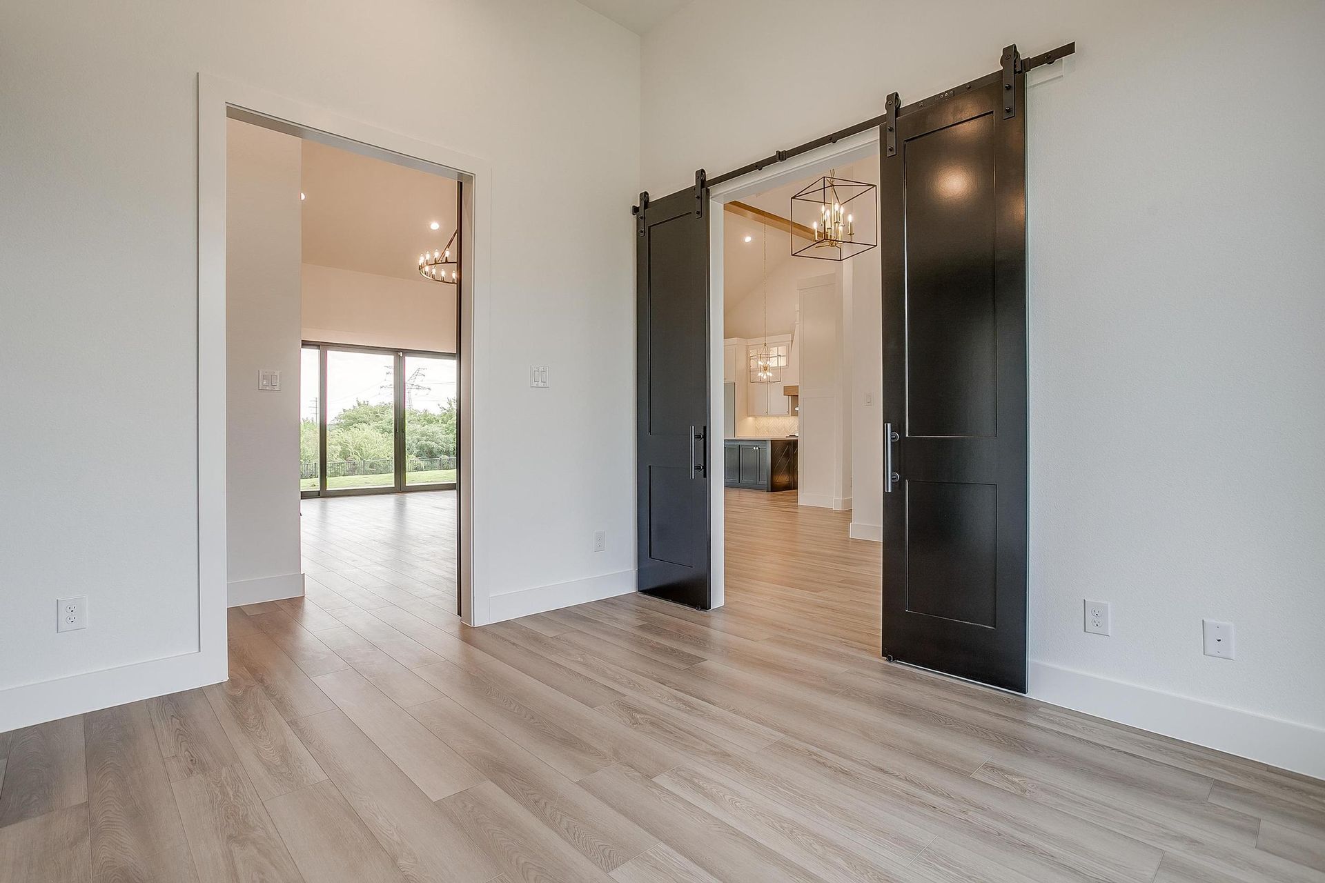 An empty room with sliding barn doors and hardwood floors.