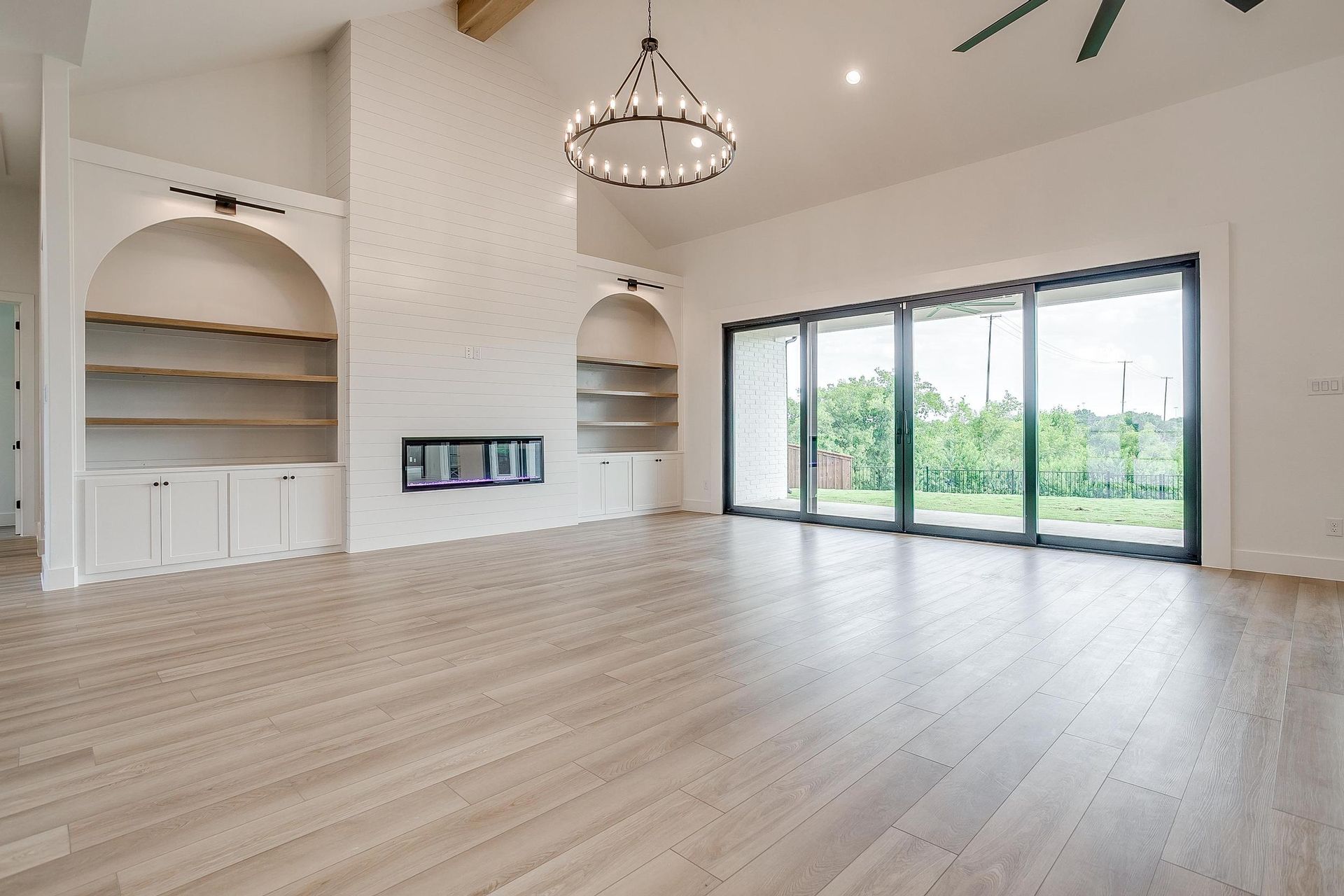 An empty living room with hardwood floors and sliding glass doors.