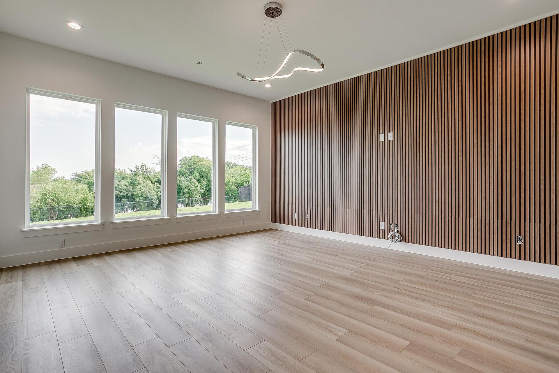 A large empty room with hardwood floors and a wooden wall.