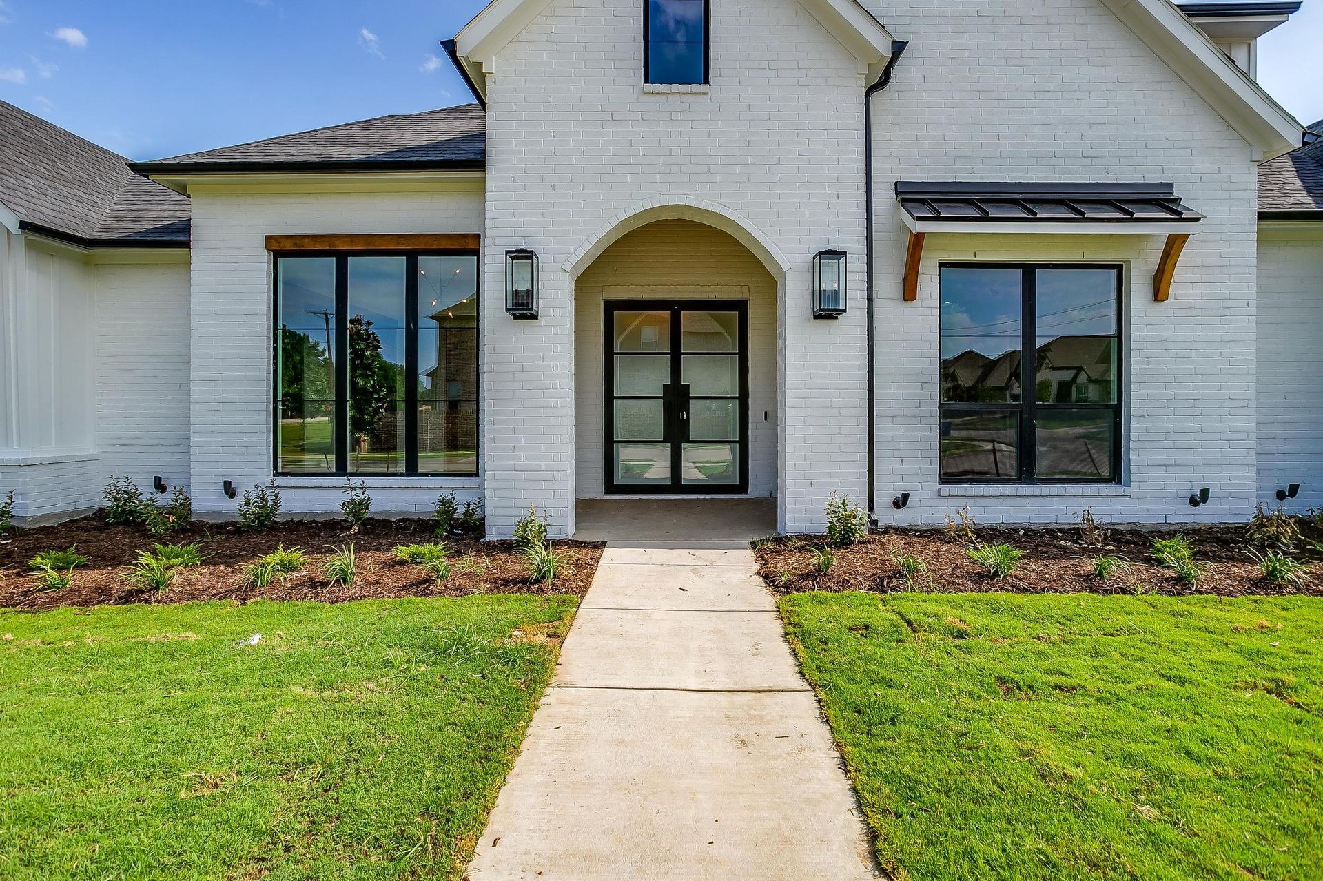 A white brick house with a walkway leading to the front door.