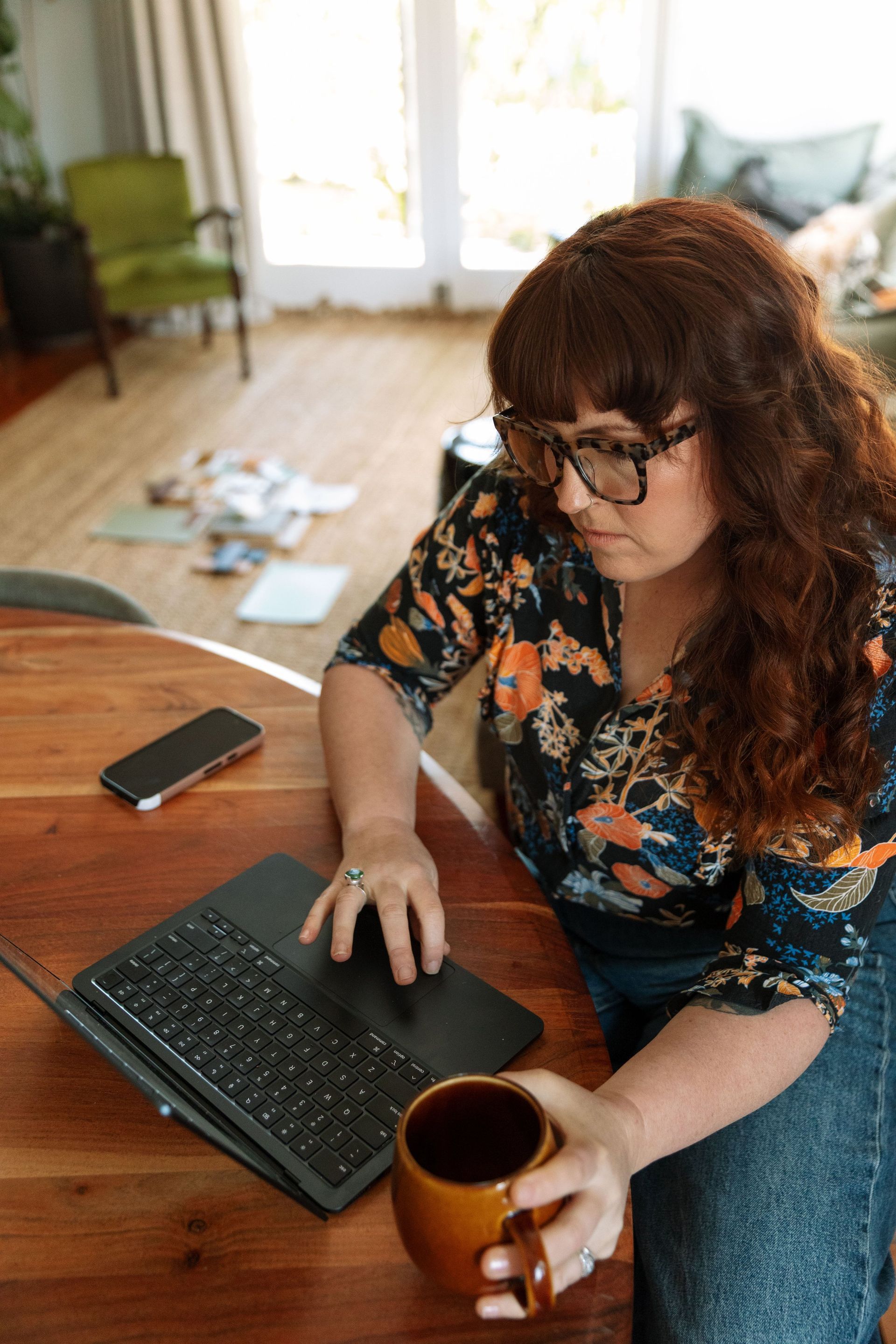 Woman Working On A Laptop At A Wooden Table, Holding A Mug — Everyday Interiors in Helensburgh, NSW