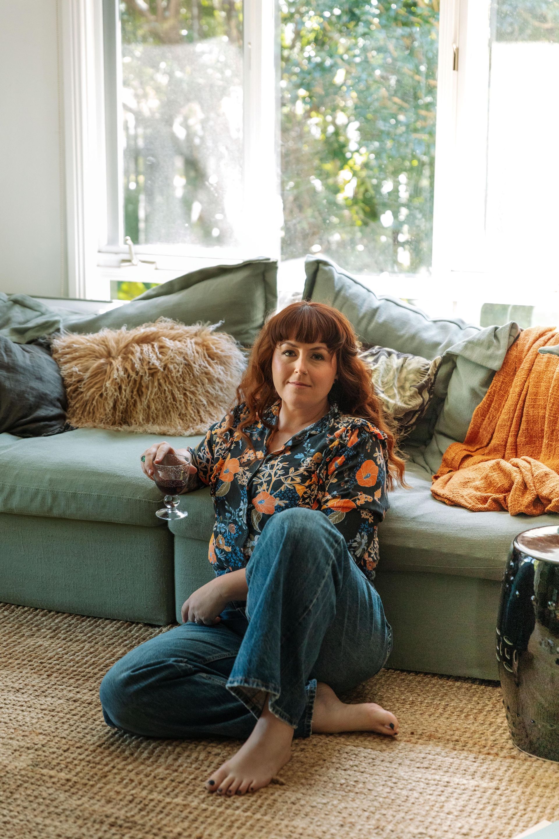 Person Sitting On A Green Couch In A Bright Living Room — Everyday Interiors in Southern Highlands, NSW