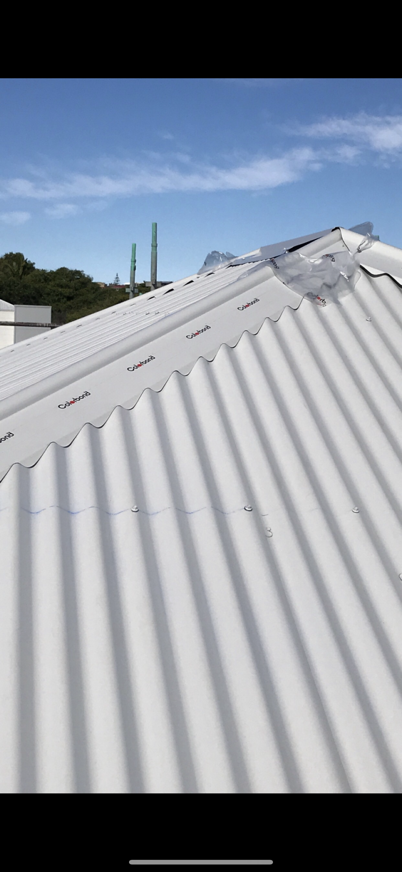 A White Corrugated Metal Roof With A Blue Sky In The Background — Premier Roofing Solutions In Lismore, NSW