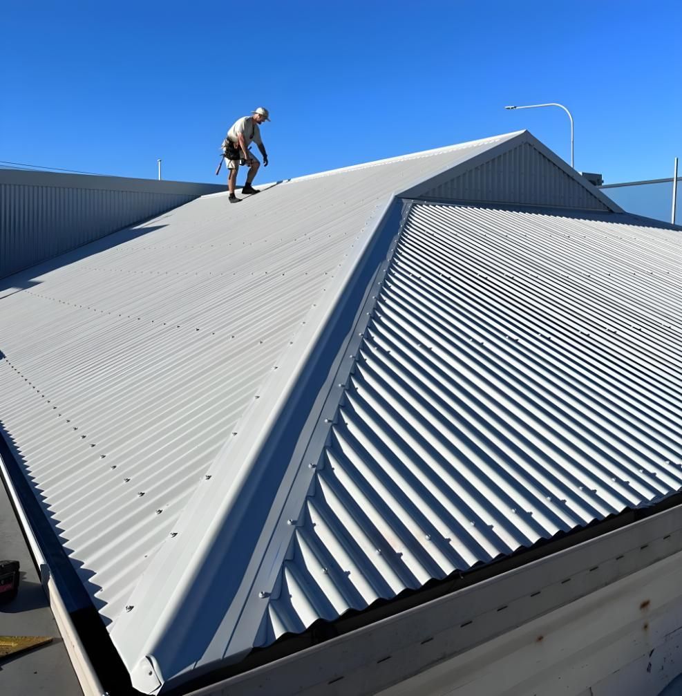 A Man Is Standing On The Roof Of A Building — Premier Roofing Solutions In Lennox Head, NSW