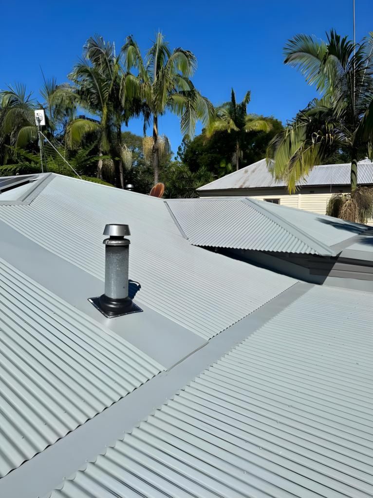 A Roof With A Chimney On It And Palm Trees In The Background — Premier Roofing Solutions In Evans Head, NSW