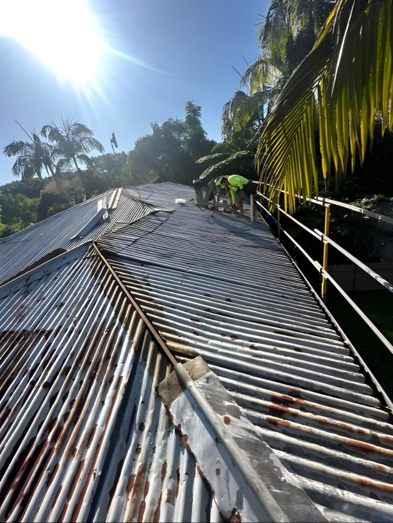 A Close Up Of A Rusty Metal Roof With Palm Trees In The Background — Premier Roofing Solutions In Lennox Head, NSW