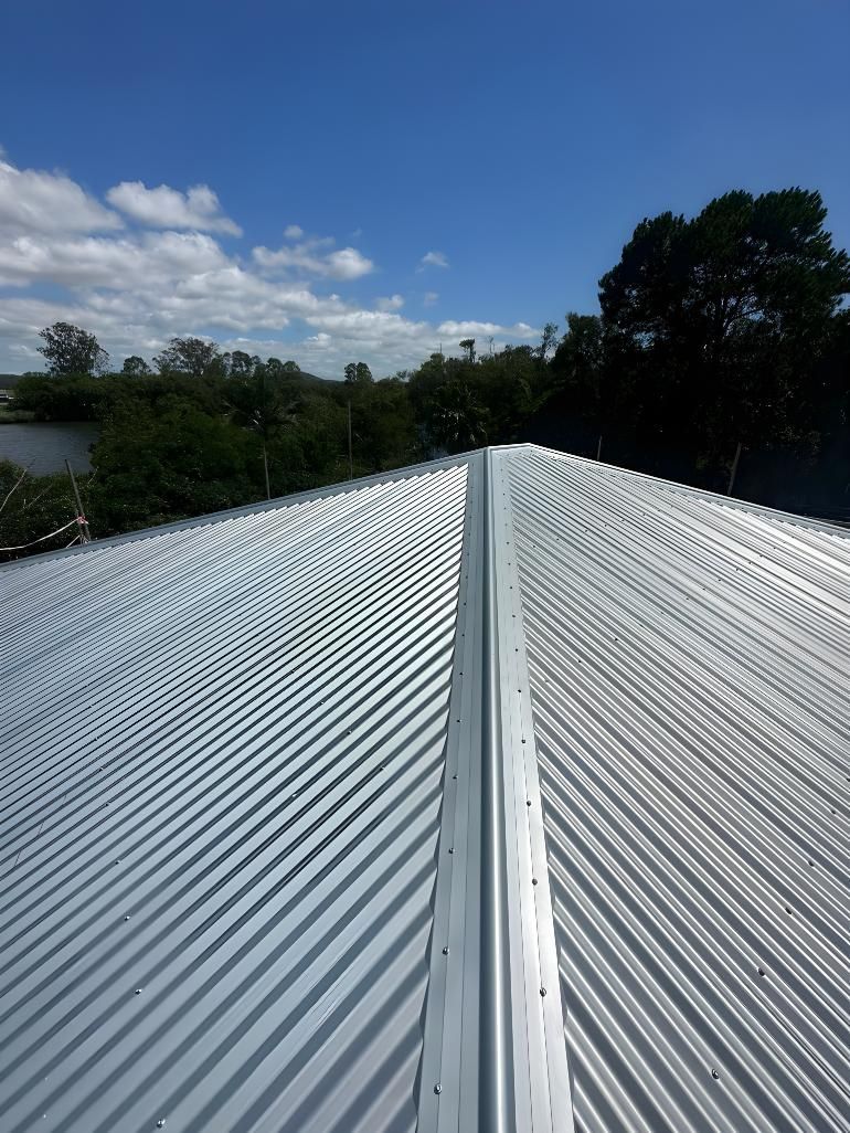 A White Corrugated Metal Roof With A Blue Sky In The Background — Premier Roofing Solutions In Lennox Head, NSW