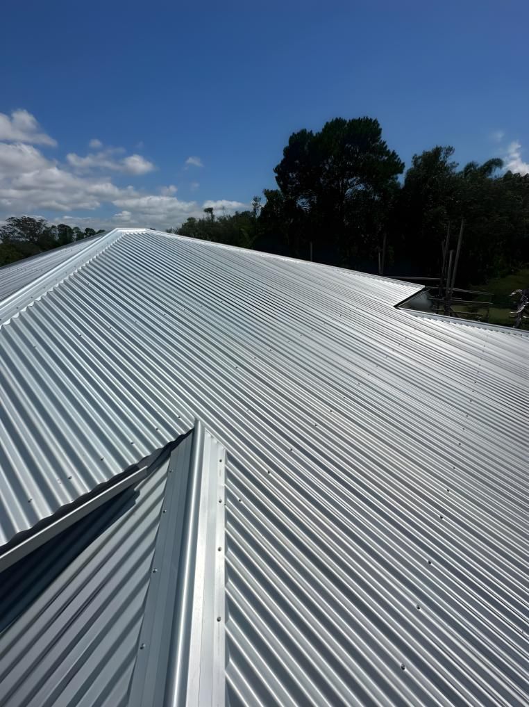 A White Corrugated Metal Roof With A Blue Sky In The Background — Premier Roofing Solutions In Tweed Heads, NSW