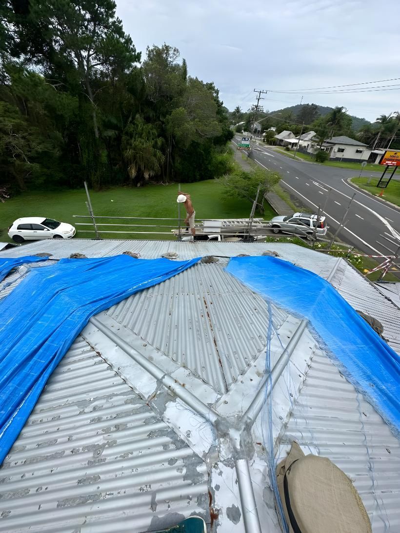 A Blue Tarp Is Covering The Roof Of A Building — Premier Roofing Solutions In Lennox Head, NSW