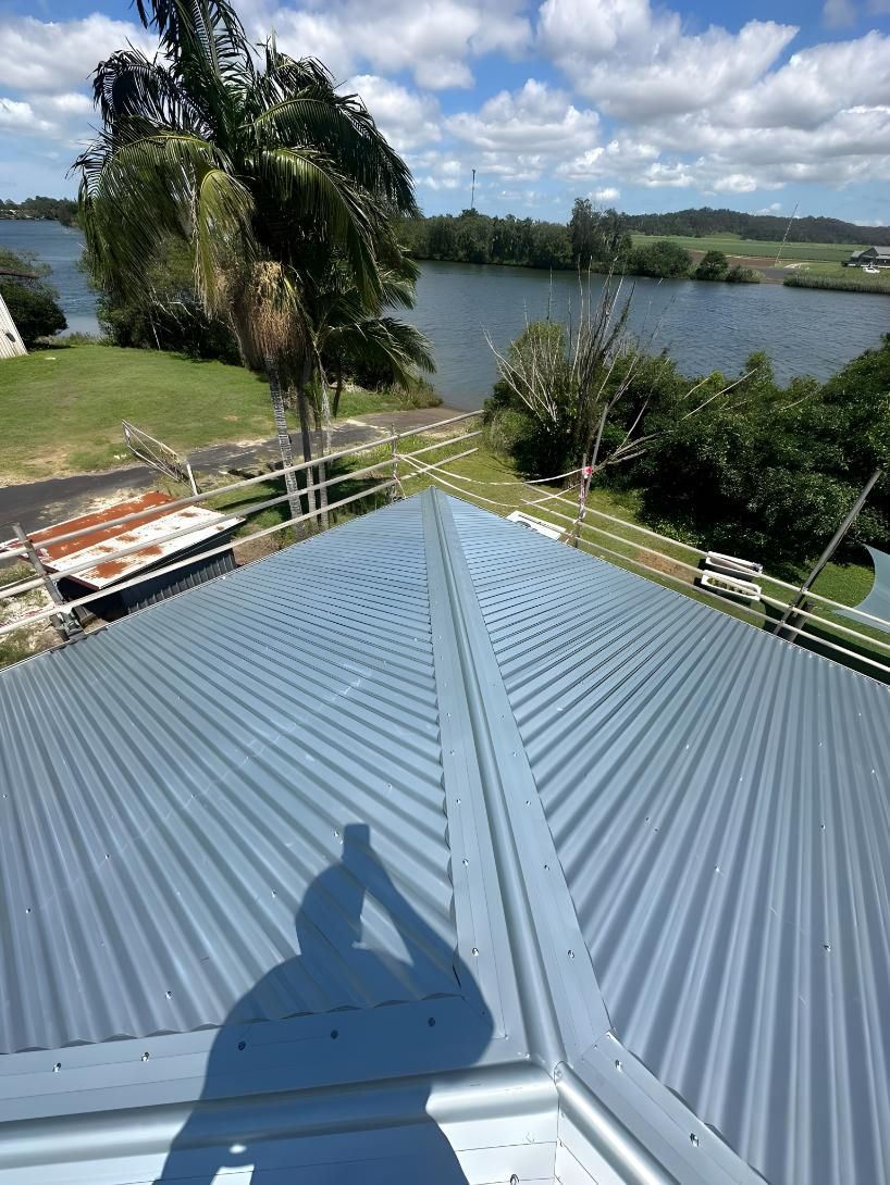 A Roof With A Shadow Of A Person On It And A River In The Background — Premier Roofing Solutions In Murwillumbah, NSW