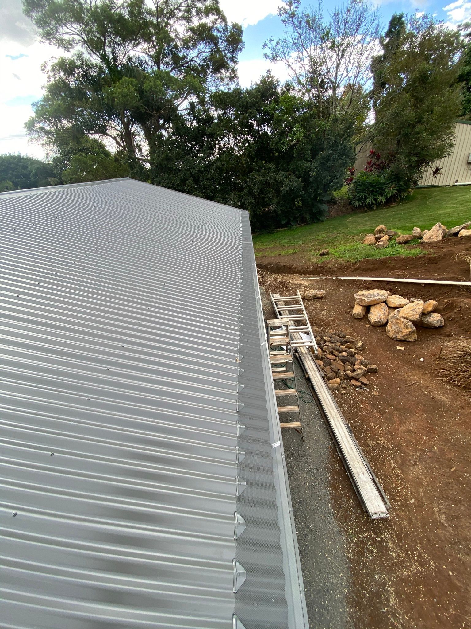 A Metal Roof Is Being Installed On A Building In A Backyard — Premier Roofing Solutions In Lennox Head, NSW