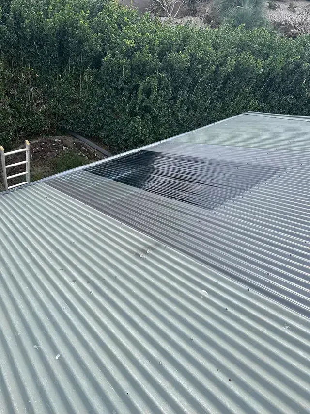 A Close Up Of A Corrugated Metal Roof With Trees In The Background — Premier Roofing Solutions In Lennox Head, NSW