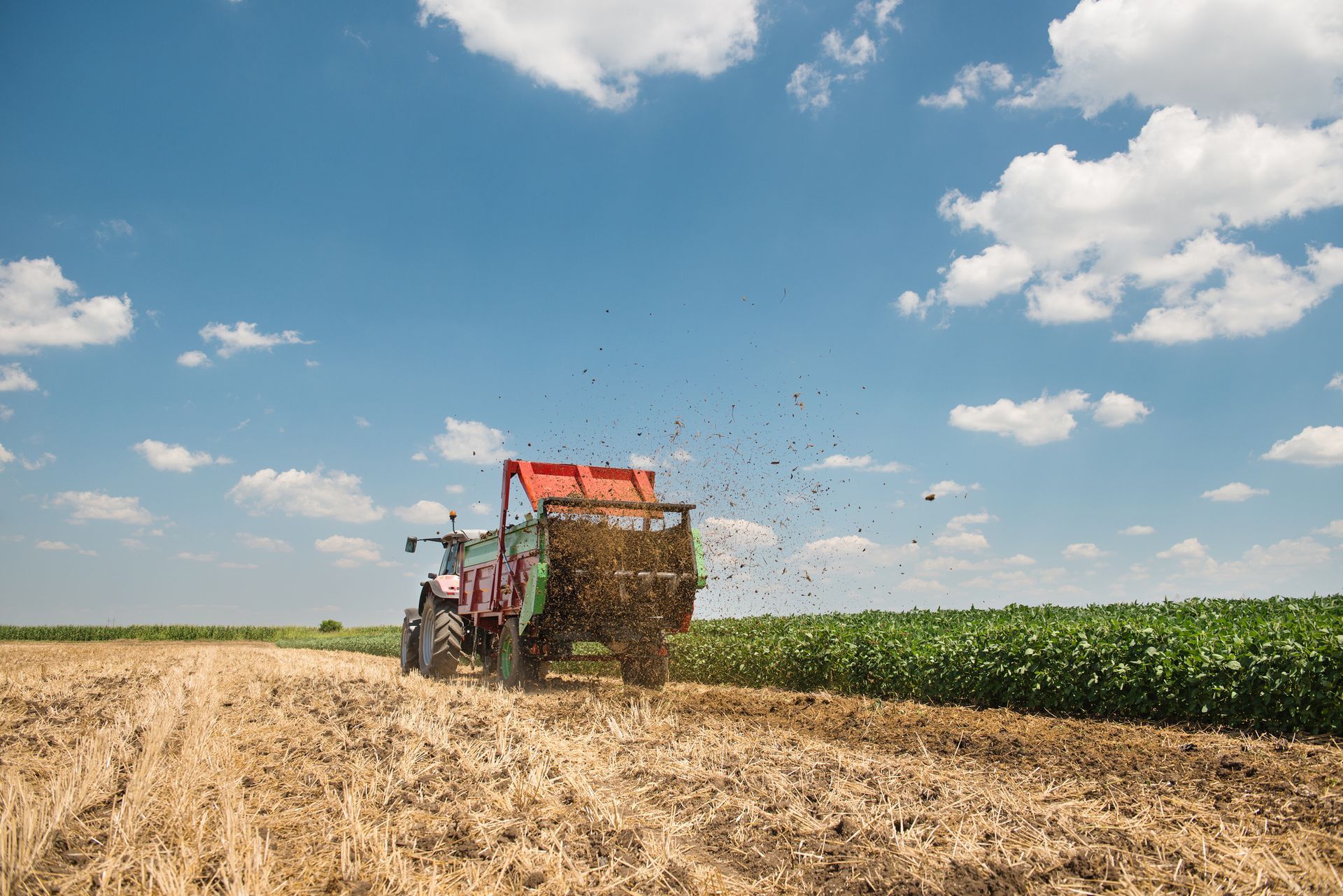Un trattore sta arando un campo in una giornata di sole.