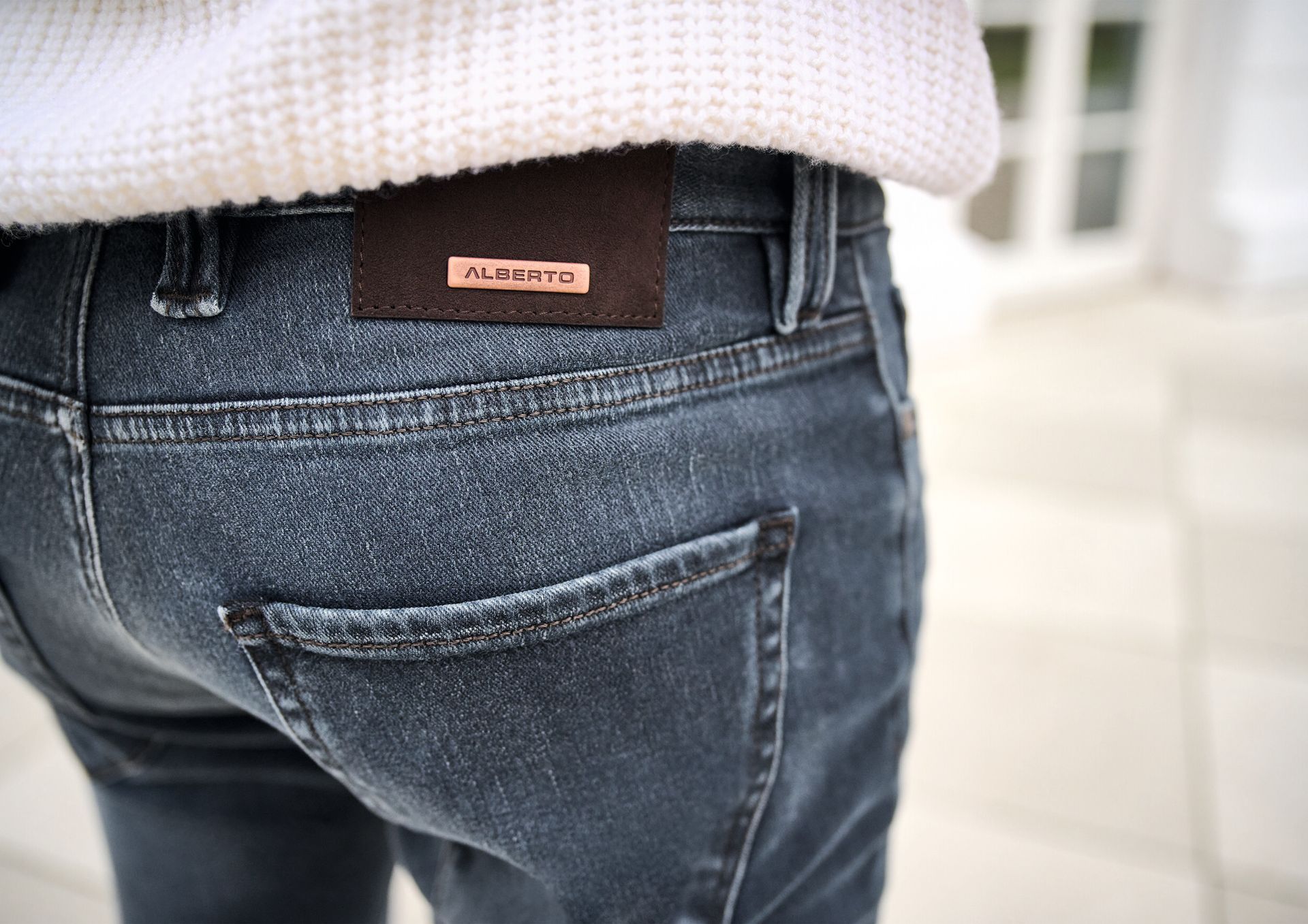 Close-up of denim jeans with a brown leather patch on the back pocket.