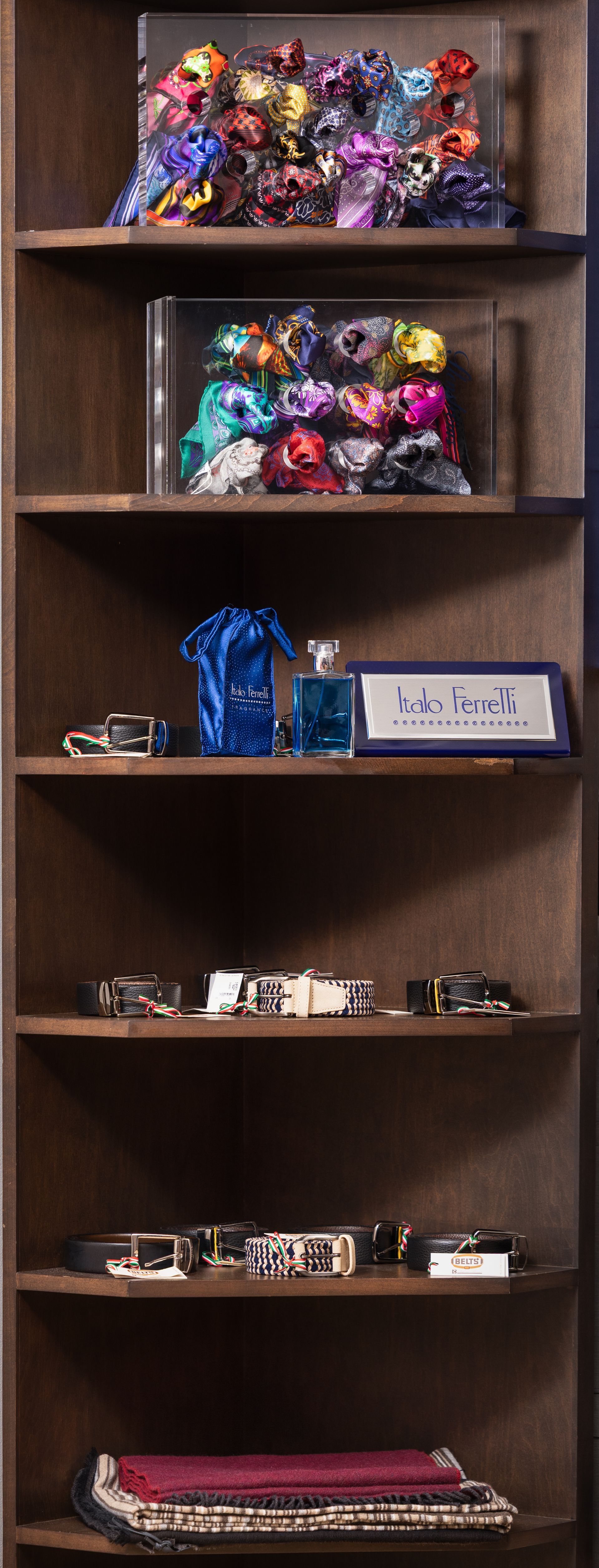 Wooden shelf with decorative items: scarves, small cameras, perfume, and a framed sign.