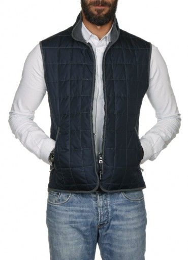 Man wearing a navy quilted vest over a white shirt and jeans.