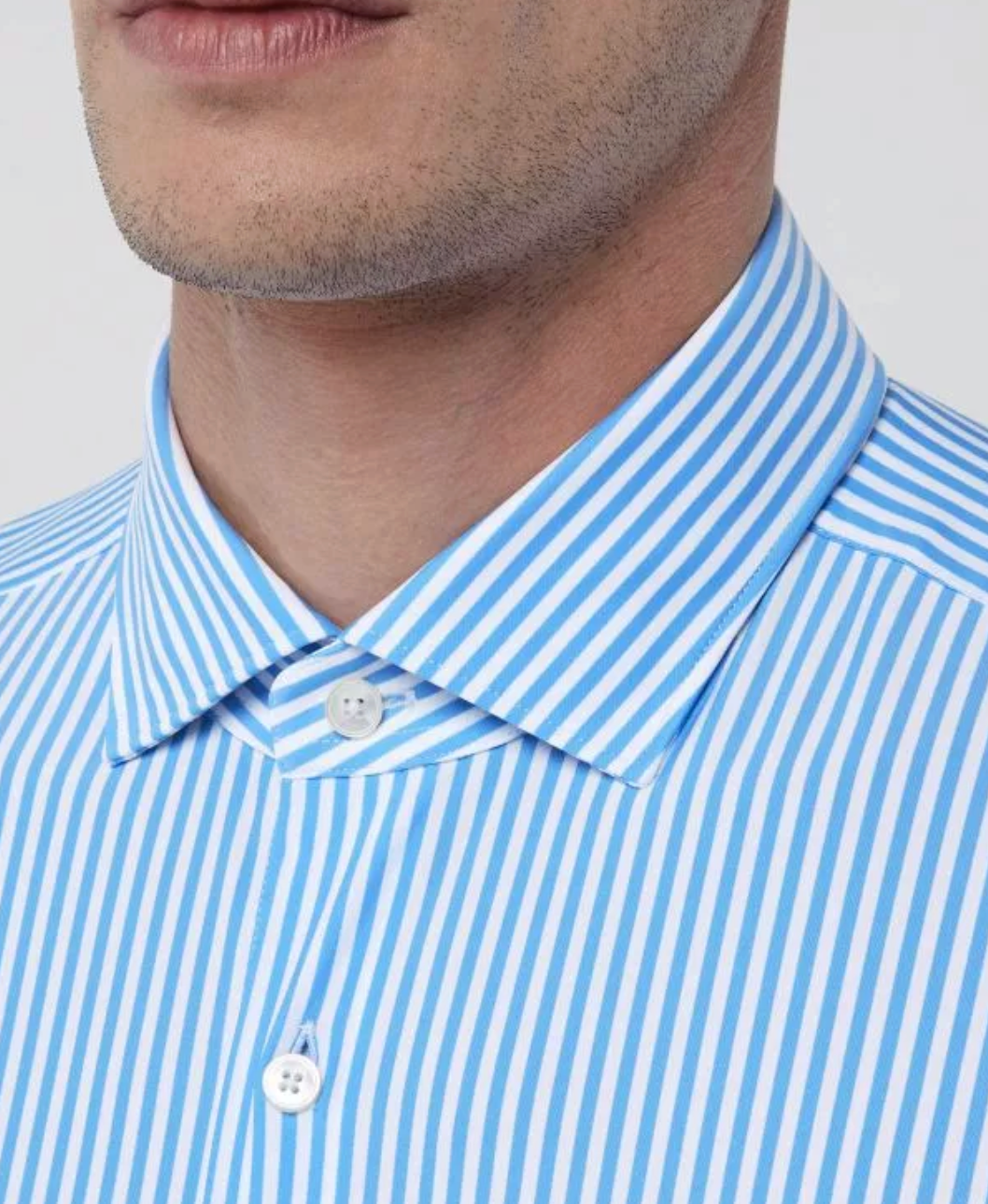 Close-up of a man wearing a blue and white striped dress shirt with a spread collar.