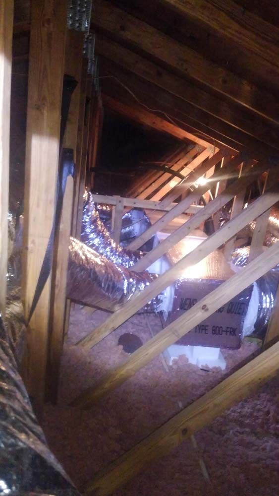 An attic with a lot of wooden beams and ducts.