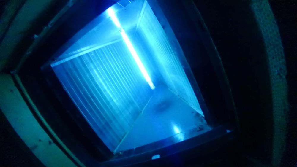 A blue light is shining through a window in a dark room.