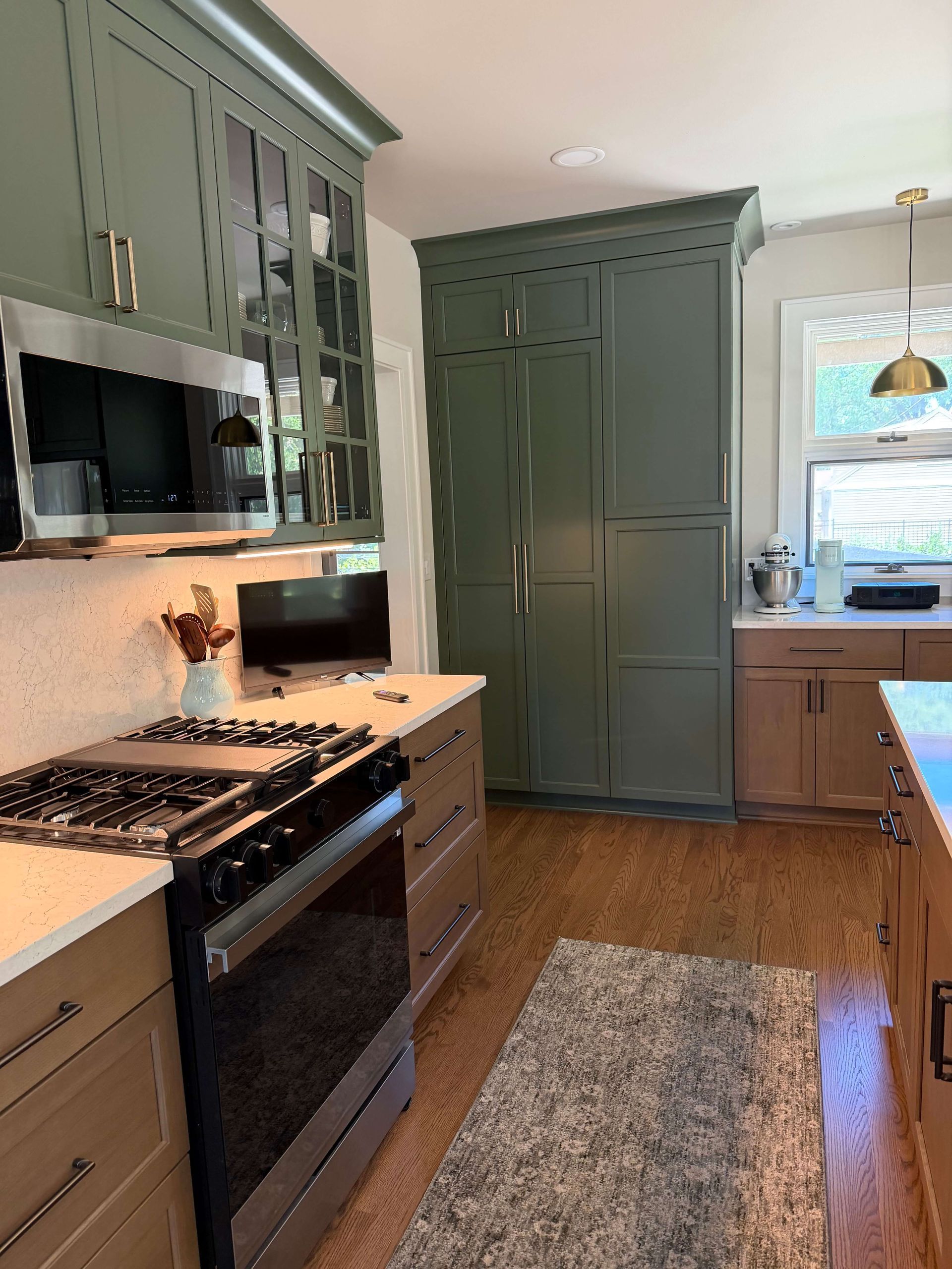 Kitchen remodeling in Glenview, IL, featuring a gray built-in beverage bar with a wine fridge, gold accents, and a mirrored backsplash in a bright hallway.