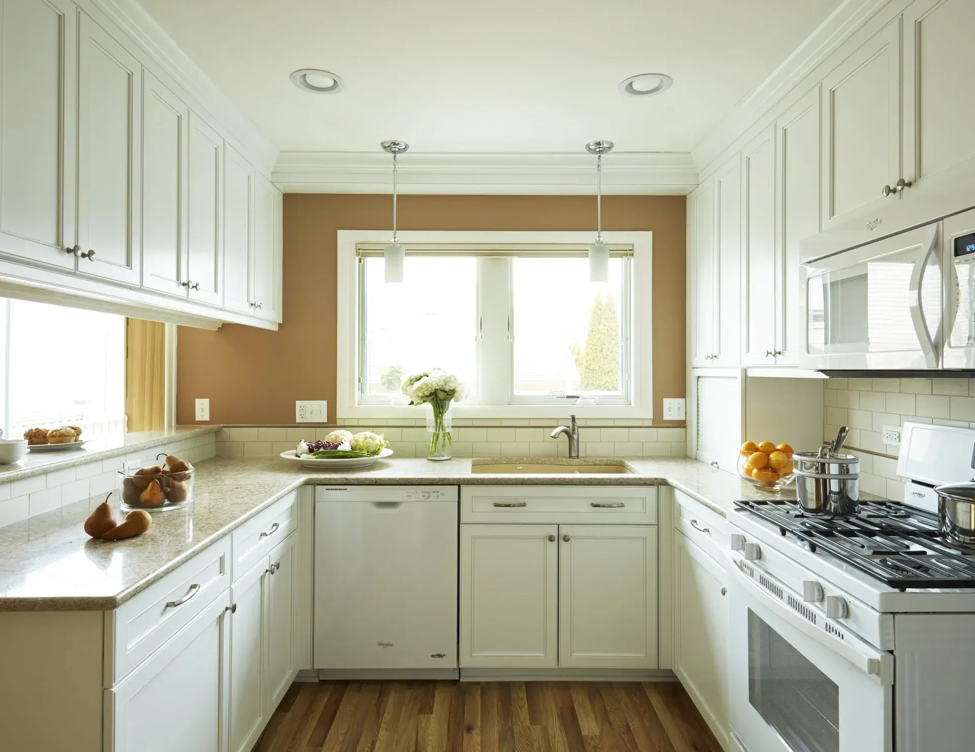 A kitchen with white cabinets a stove a sink and a window