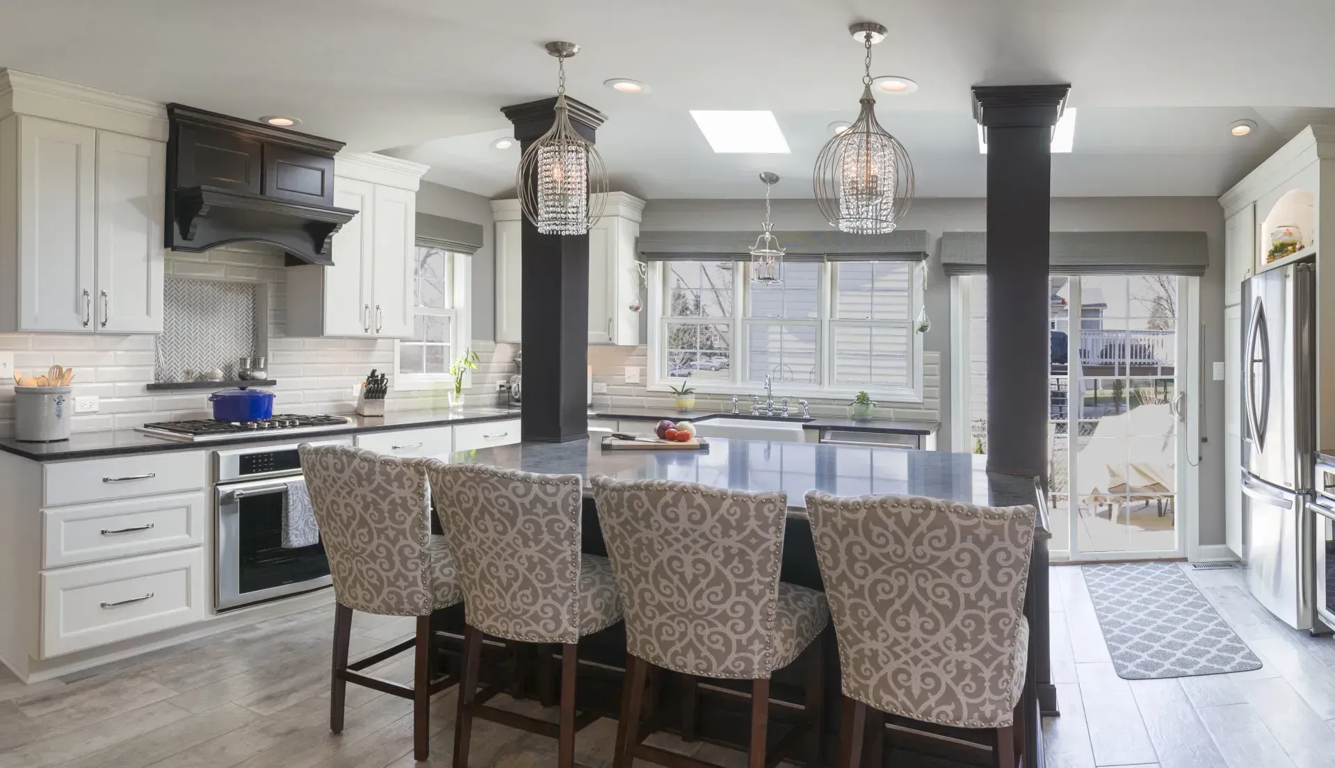 A kitchen with white cabinets , black counter tops , and a large island.