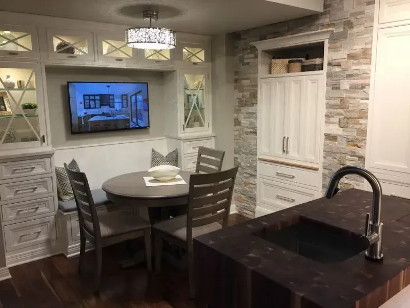A kitchen with a table , chairs , sink and television.
