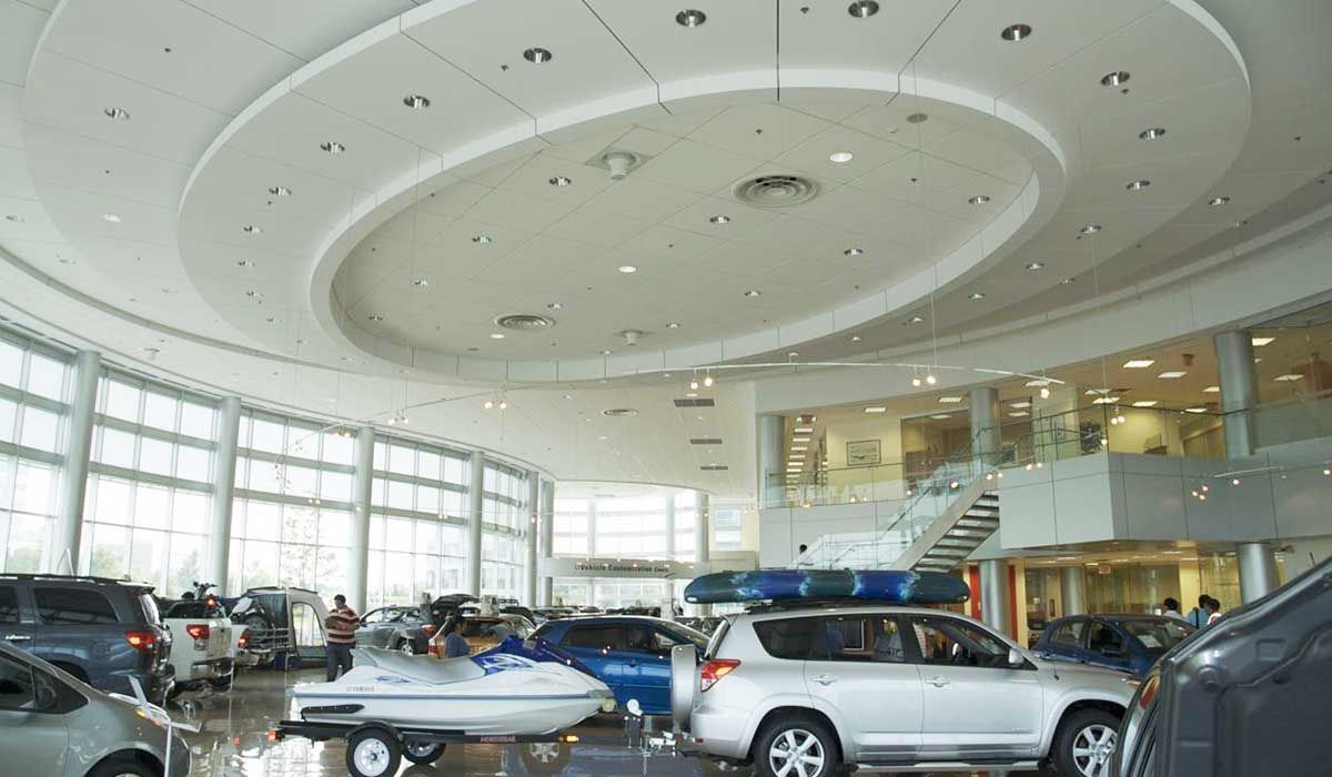 Inside a Volkswagen Showroom looking at the white roof . Volkswagen cars are parked throughout the showroom