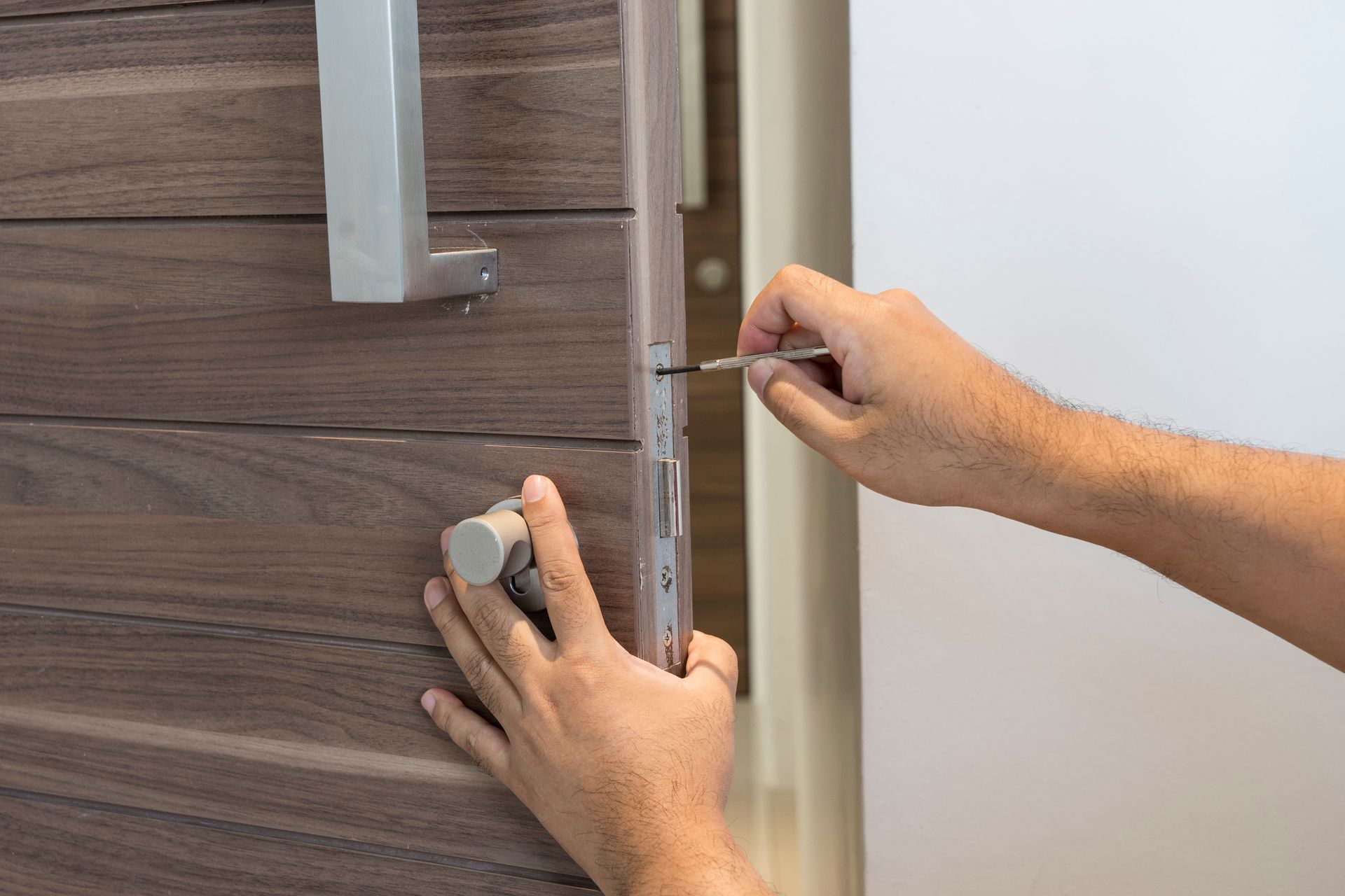 Professional commercial locksmith tightening screws on a secure building door.
