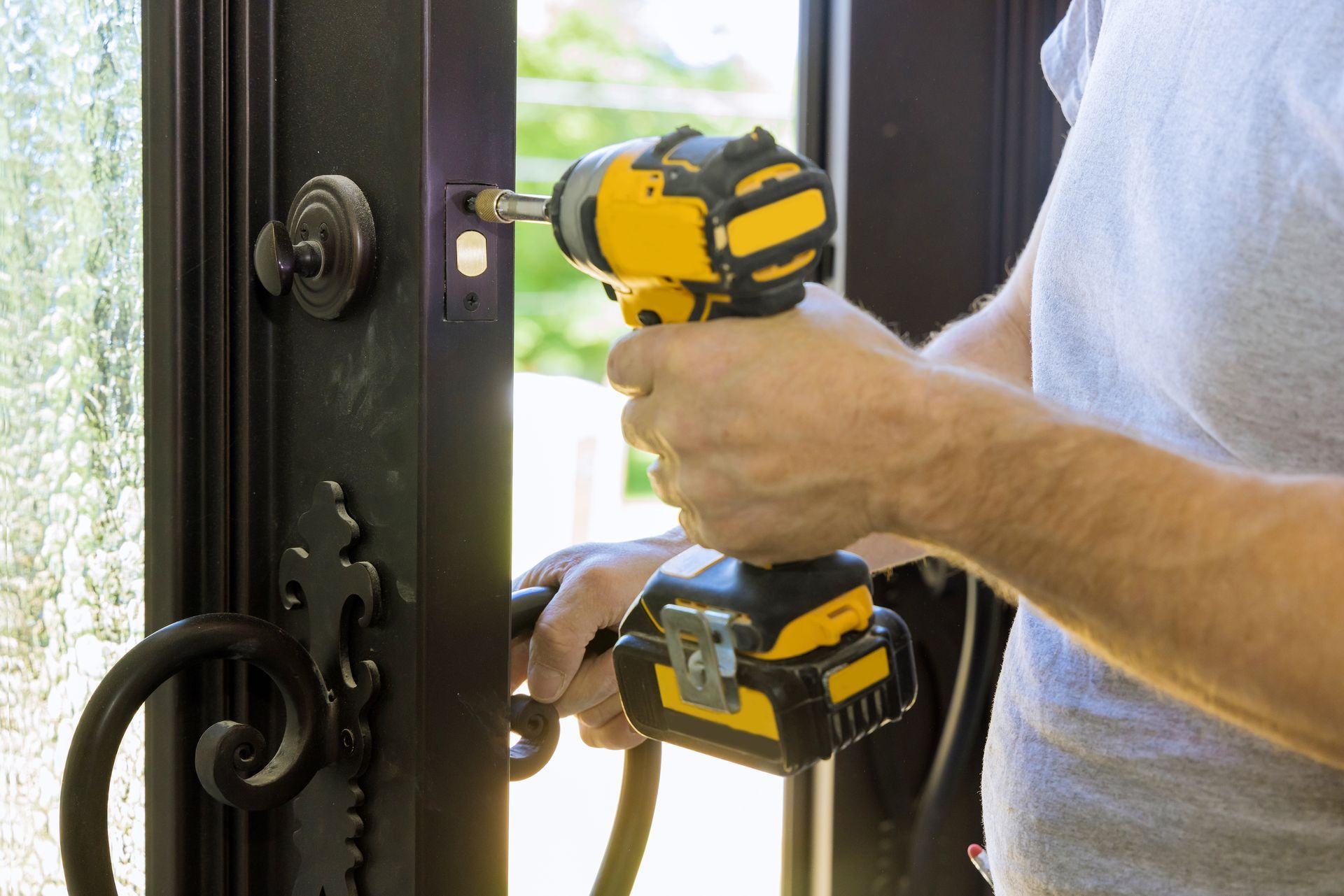 The locksmith installs a new door lock with a cordless drill at the home entrance. The locksmith installs a new door lock with a cordless drill at the home entrance.