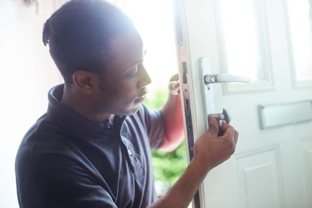 Person fixing a door lock with screwdriver during home security repair.