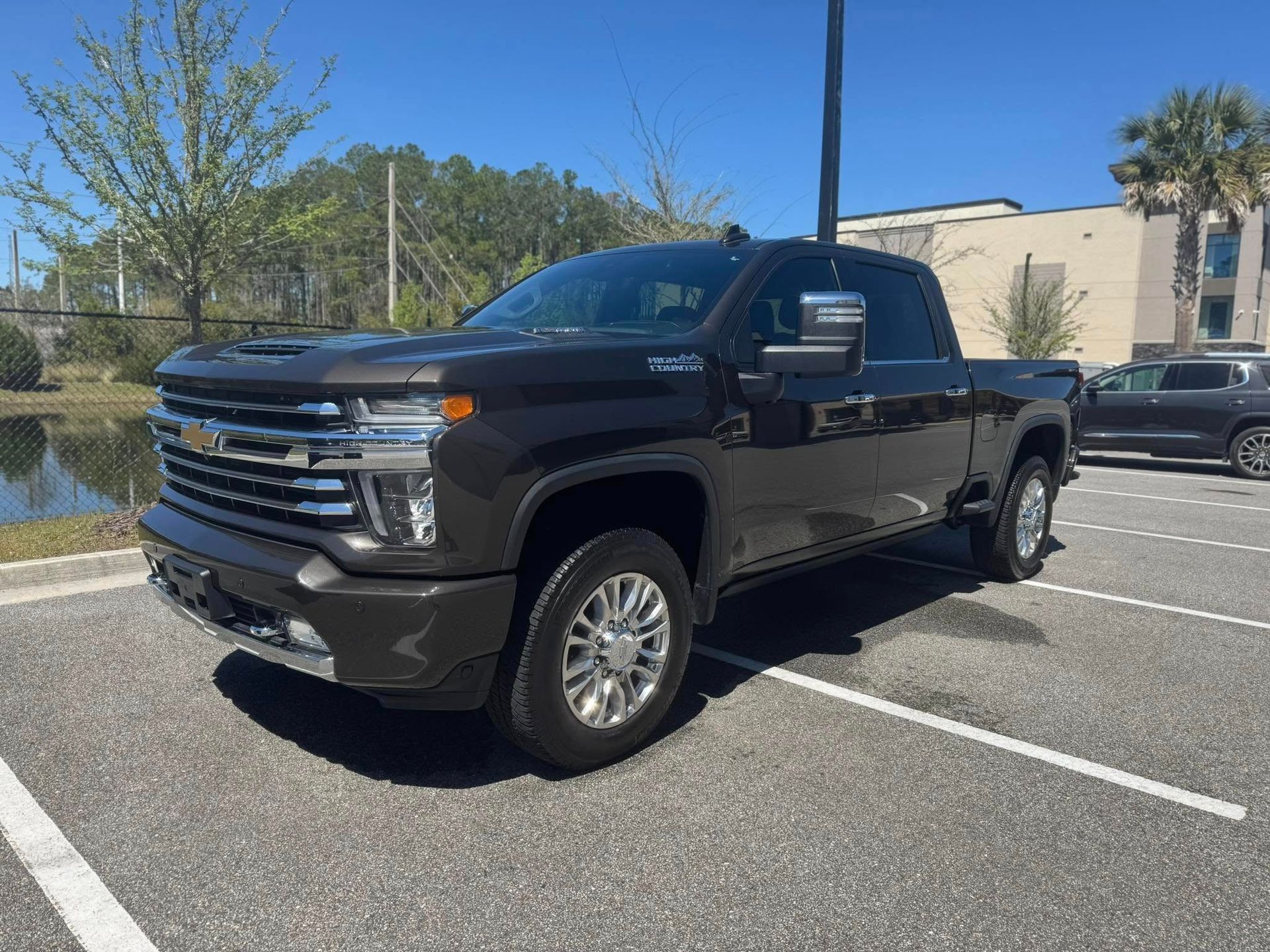 A black pickup truck is parked in a parking lot next to a body of water.