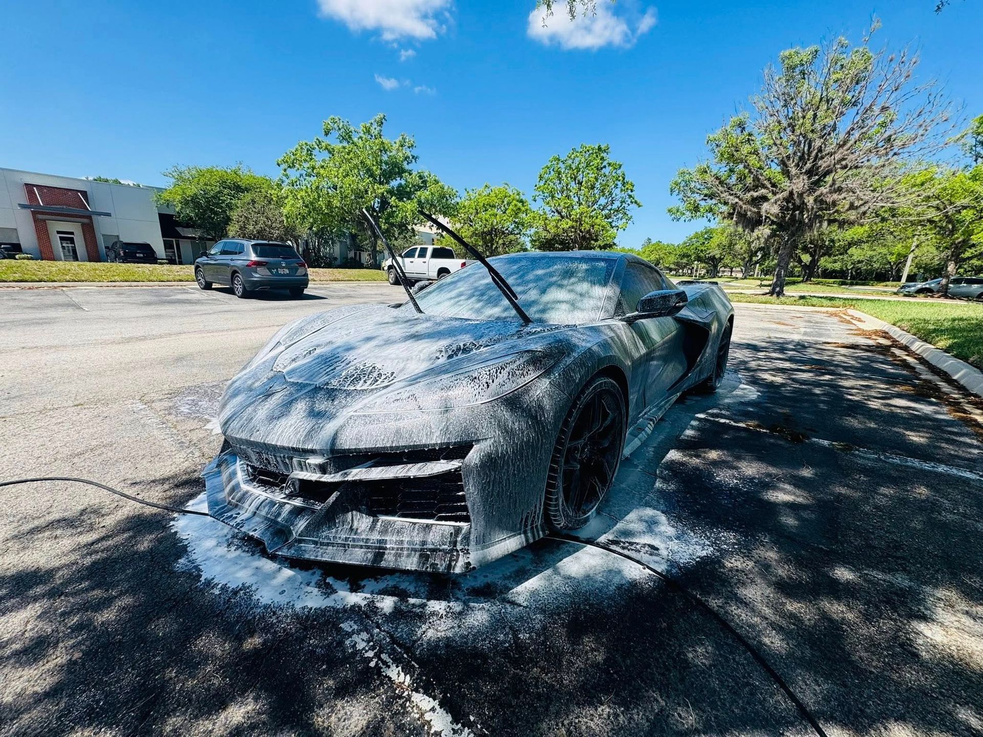 A black sports car is parked in a parking lot. A black sports car is parked in a parking lot.
