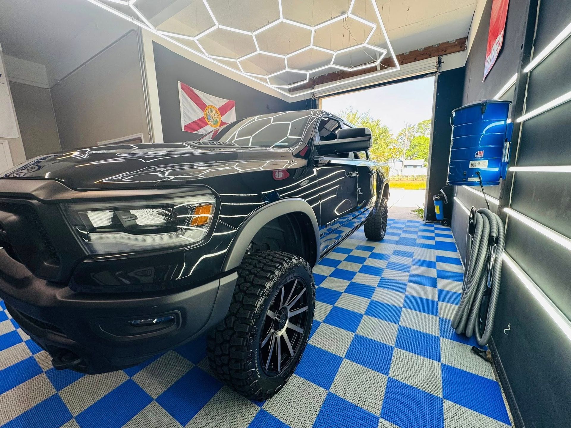 A black truck is parked in a garage with a checkered floor.