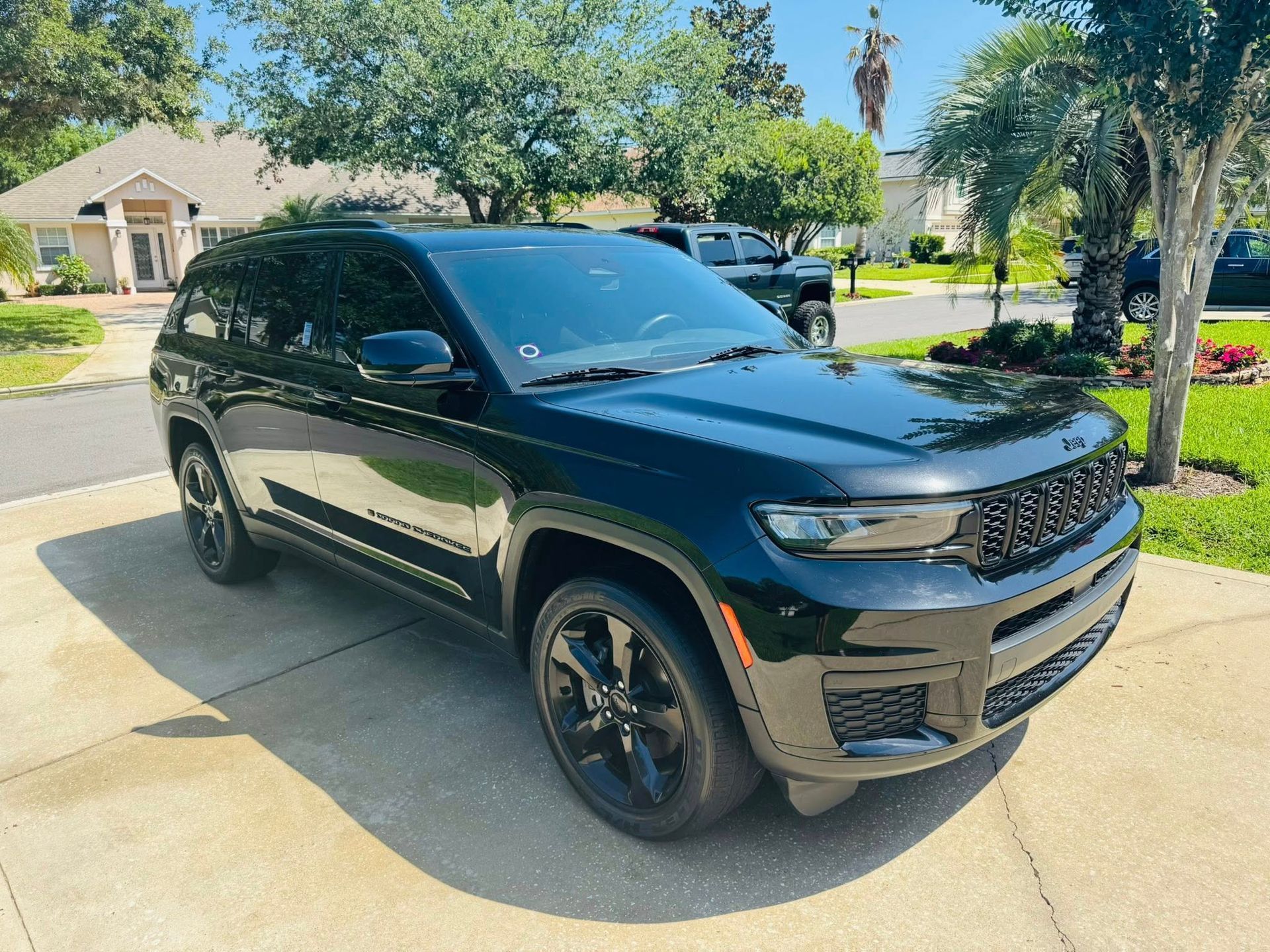 A black jeep grand cherokee is parked in a driveway in front of a house.