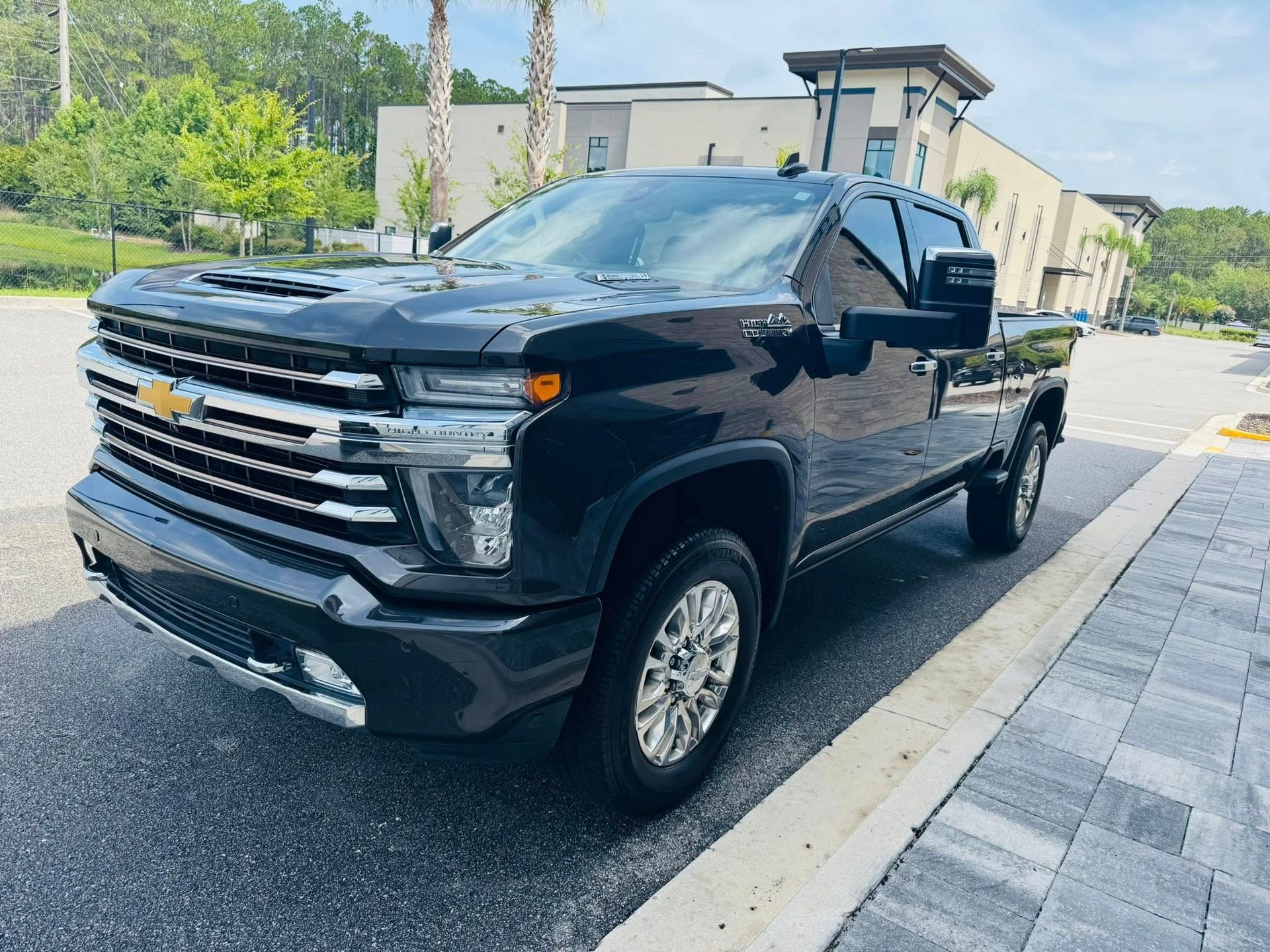 A black truck is parked on the side of the road in front of a building.