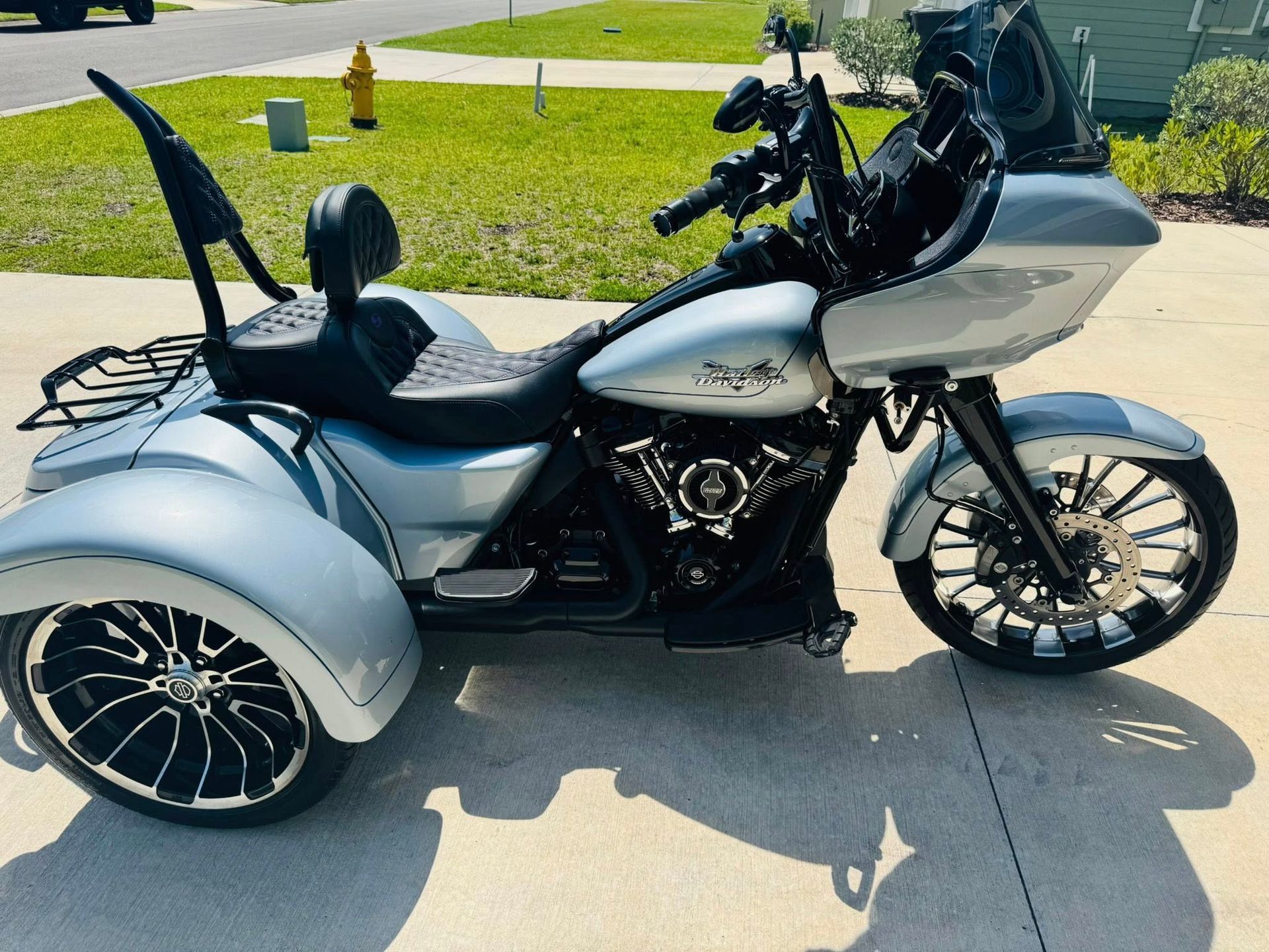 A motorcycle with three wheels is parked in a driveway.