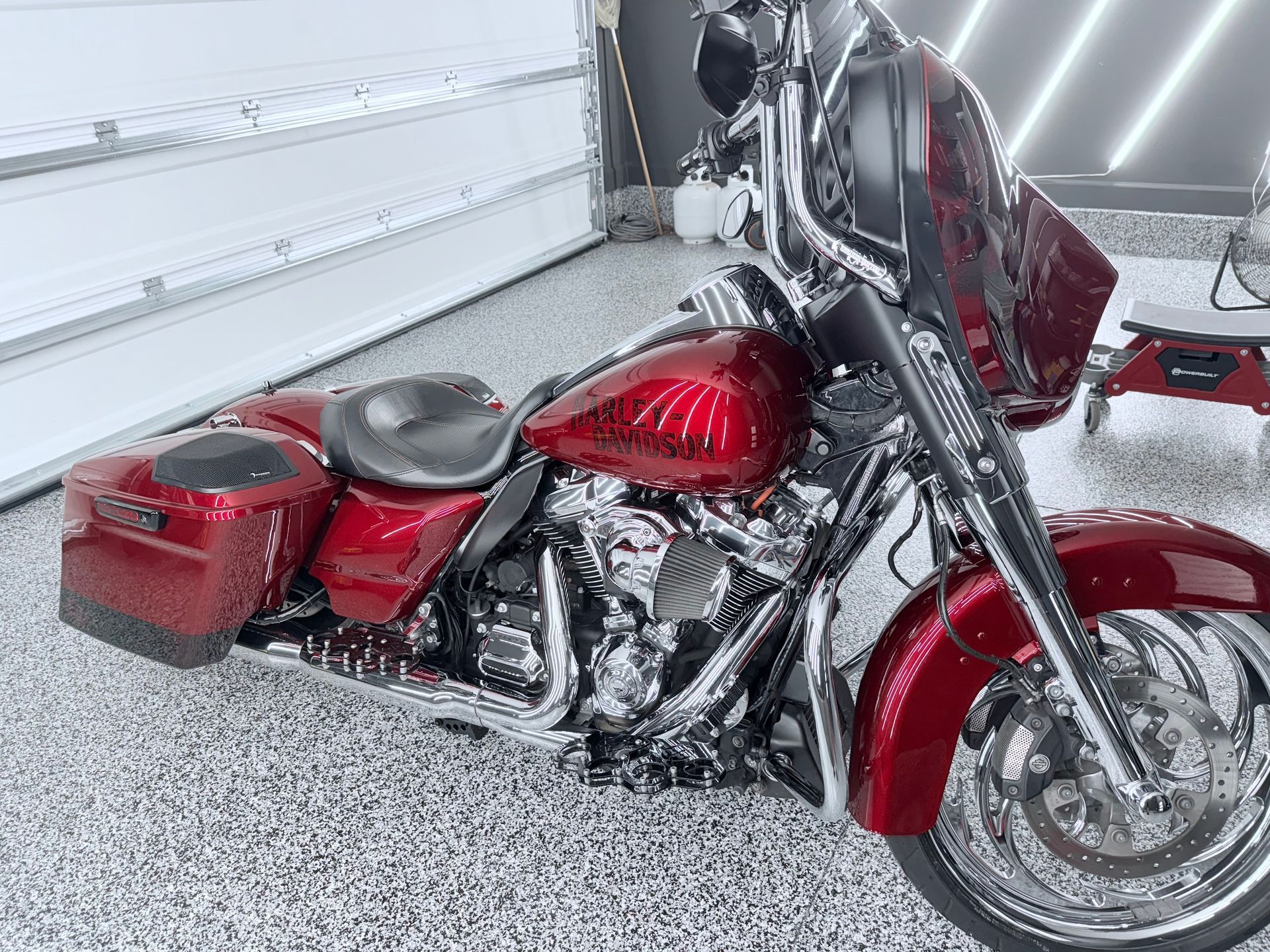 A black corvette convertible is parked in a driveway next to a white truck.