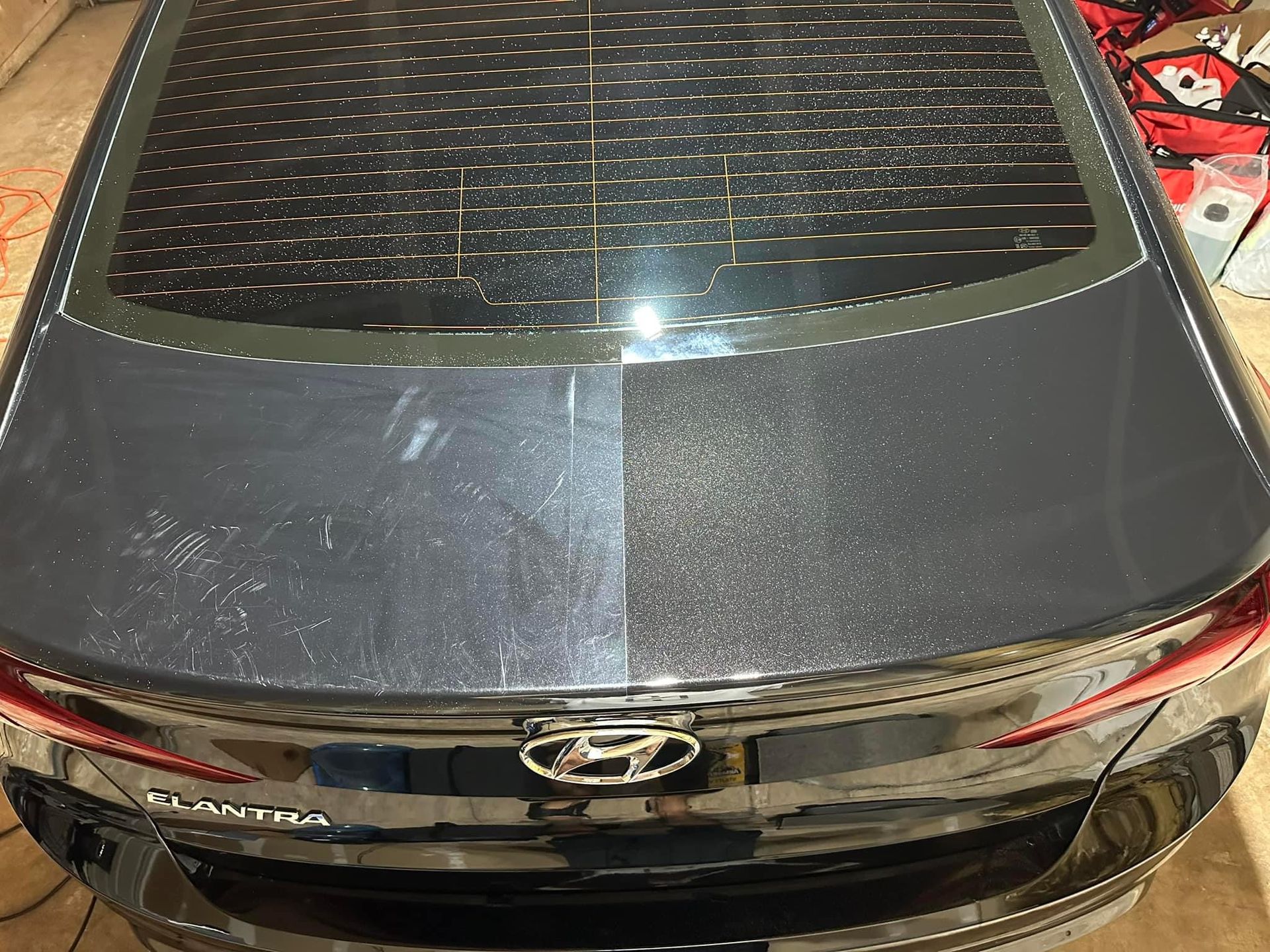 A black car is parked in a driveway in front of a house.